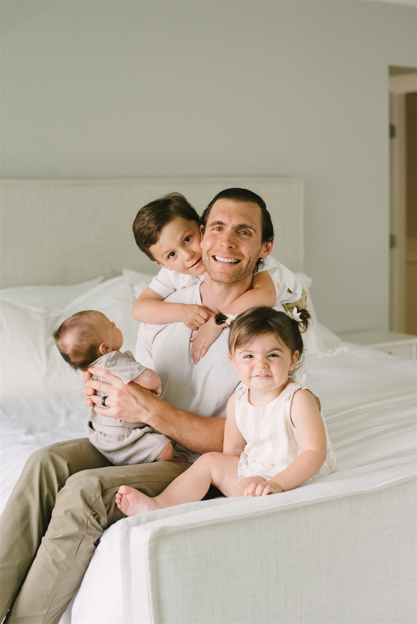 Dad sitting with kids on bed during family session with NKB Photo