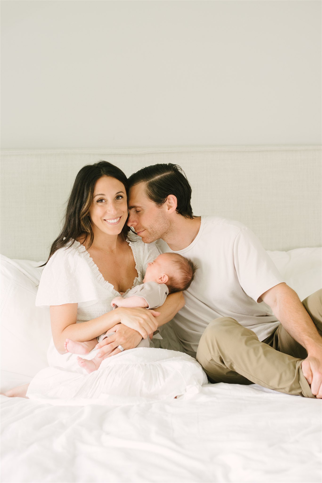 Mom and dad on bed with newborn during Boca Raton family session