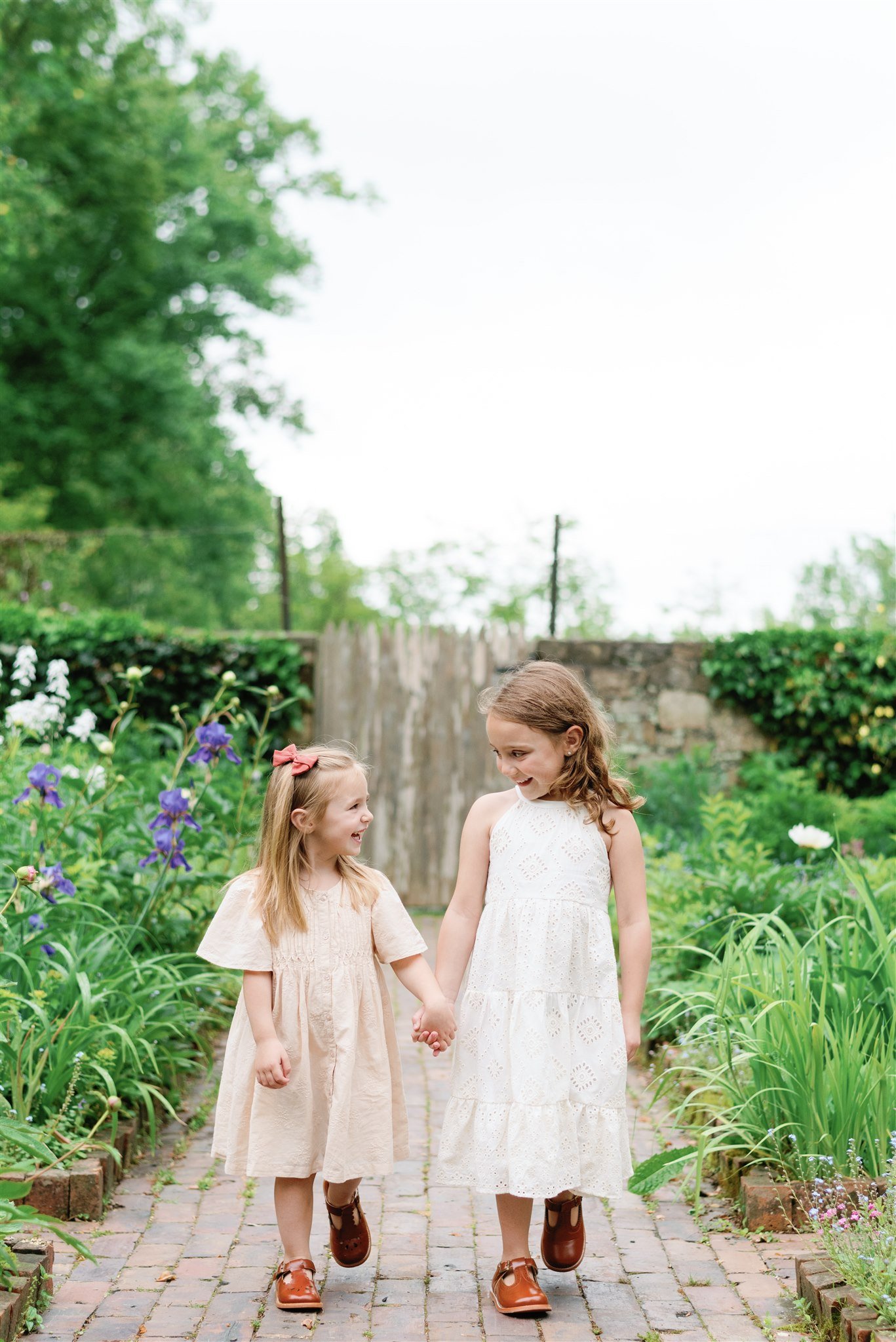 Sisters holding hands in garden during session with NKB Photo