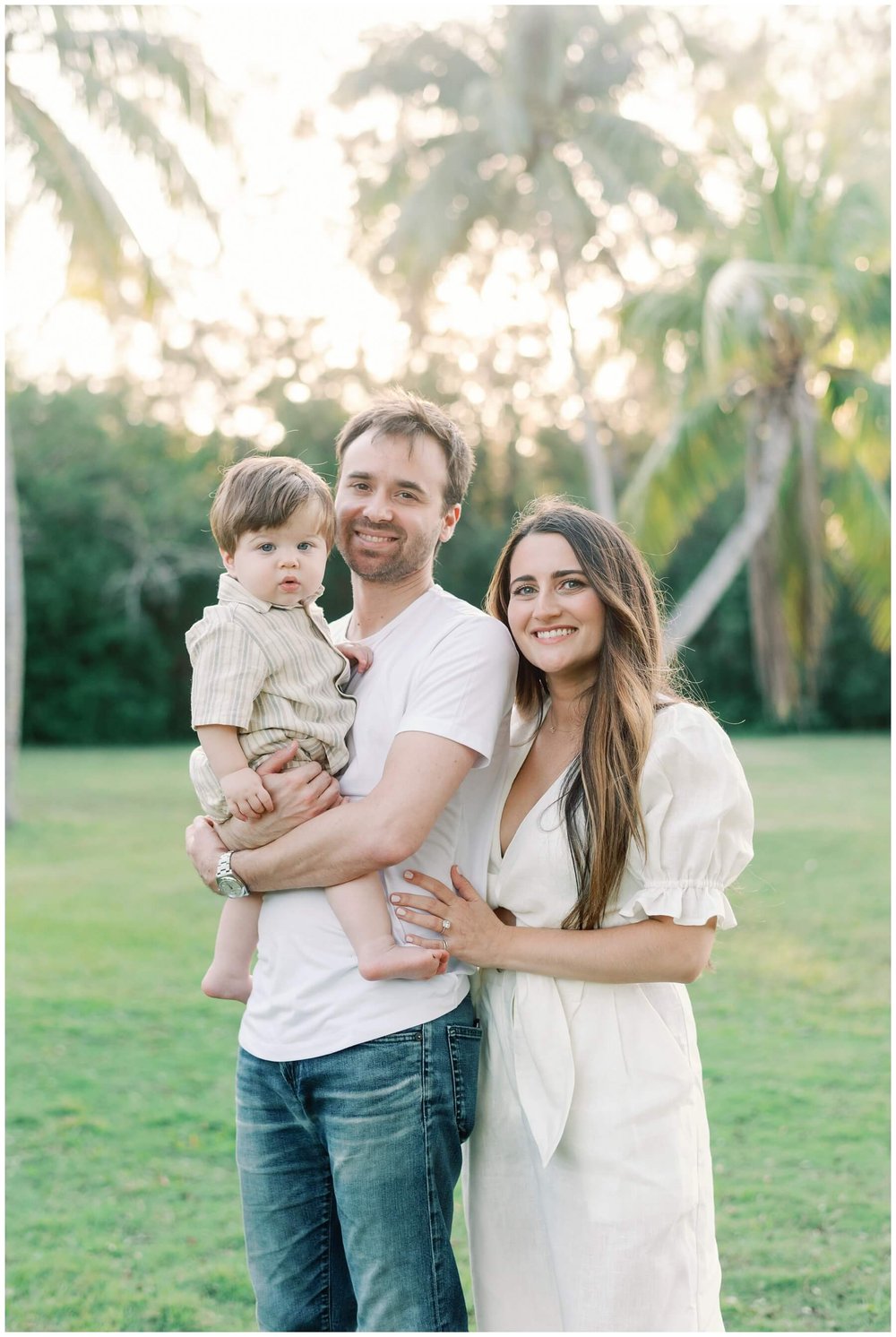 Dad holding one year old while mom stands next to them during session with family photographer in Miami | NKB Photo