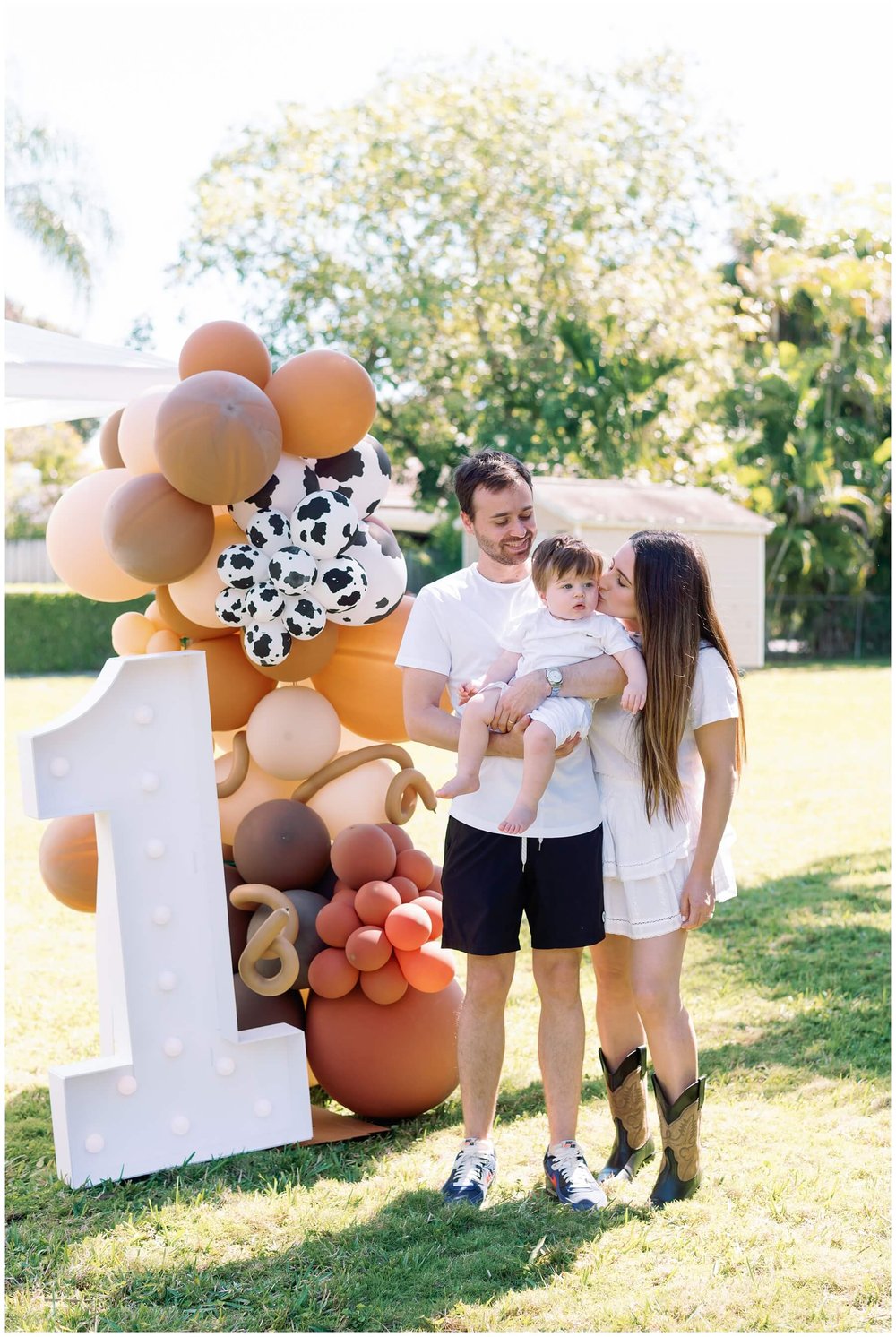 One year old and parents standing in front of balloon display at first birthday | NKB Photo