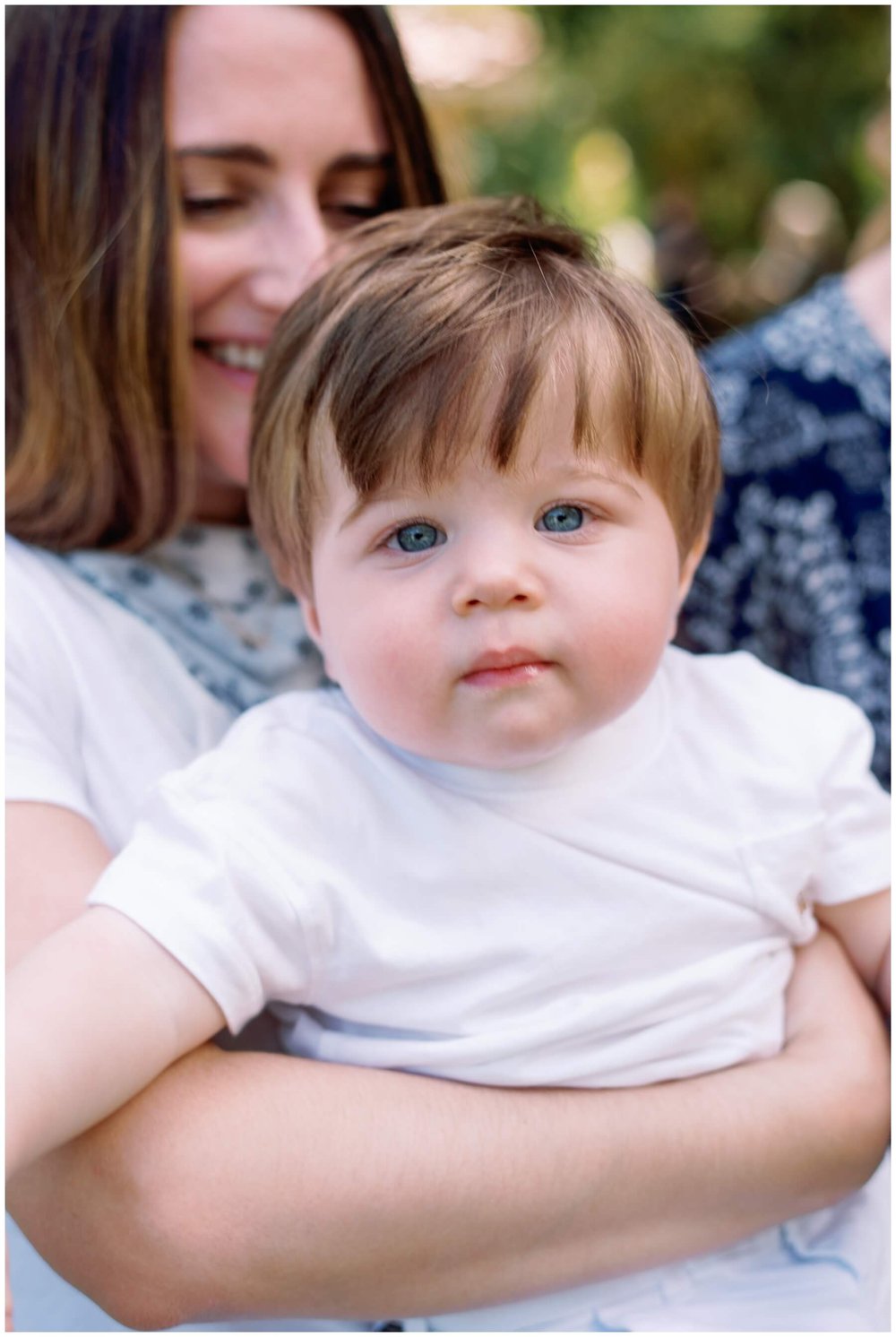 Mom holding one year old while he looks at the camera | NKB Photo