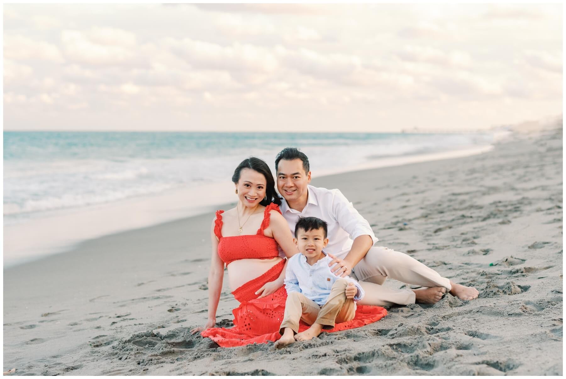 Family sitting on beach during maternity session | NKB Photo