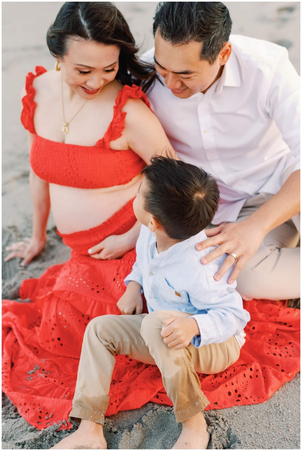 Mom and dad looking down at son on the beach during session with maternity photographer in Miami | NKB Photo