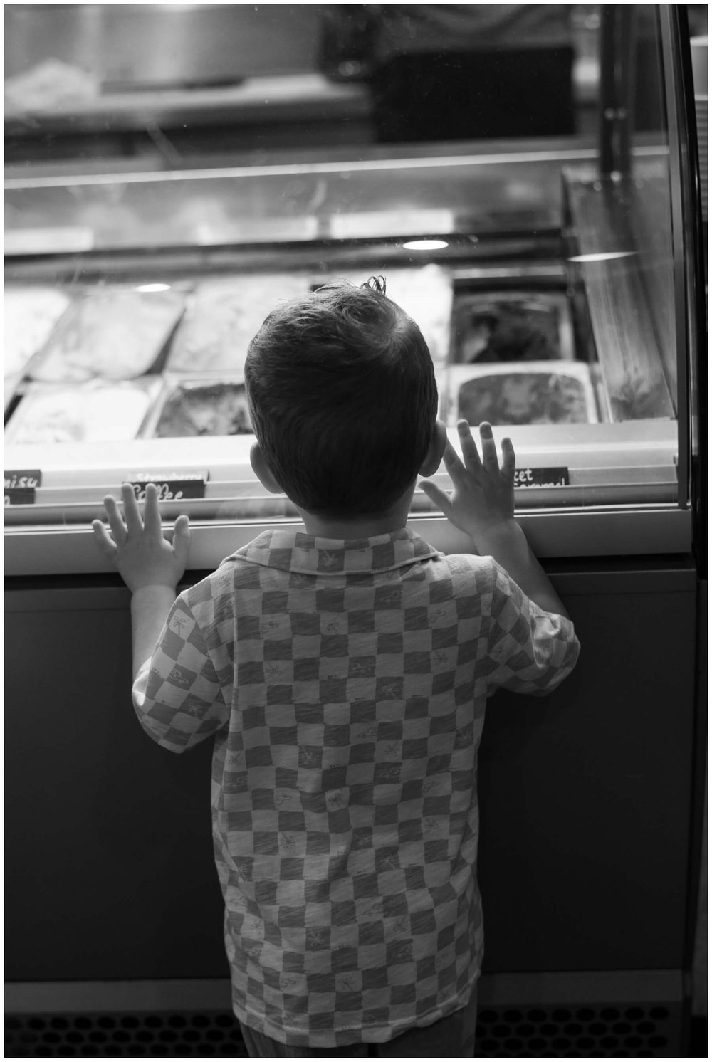 Boy standing with hands on glass looking at ice cream