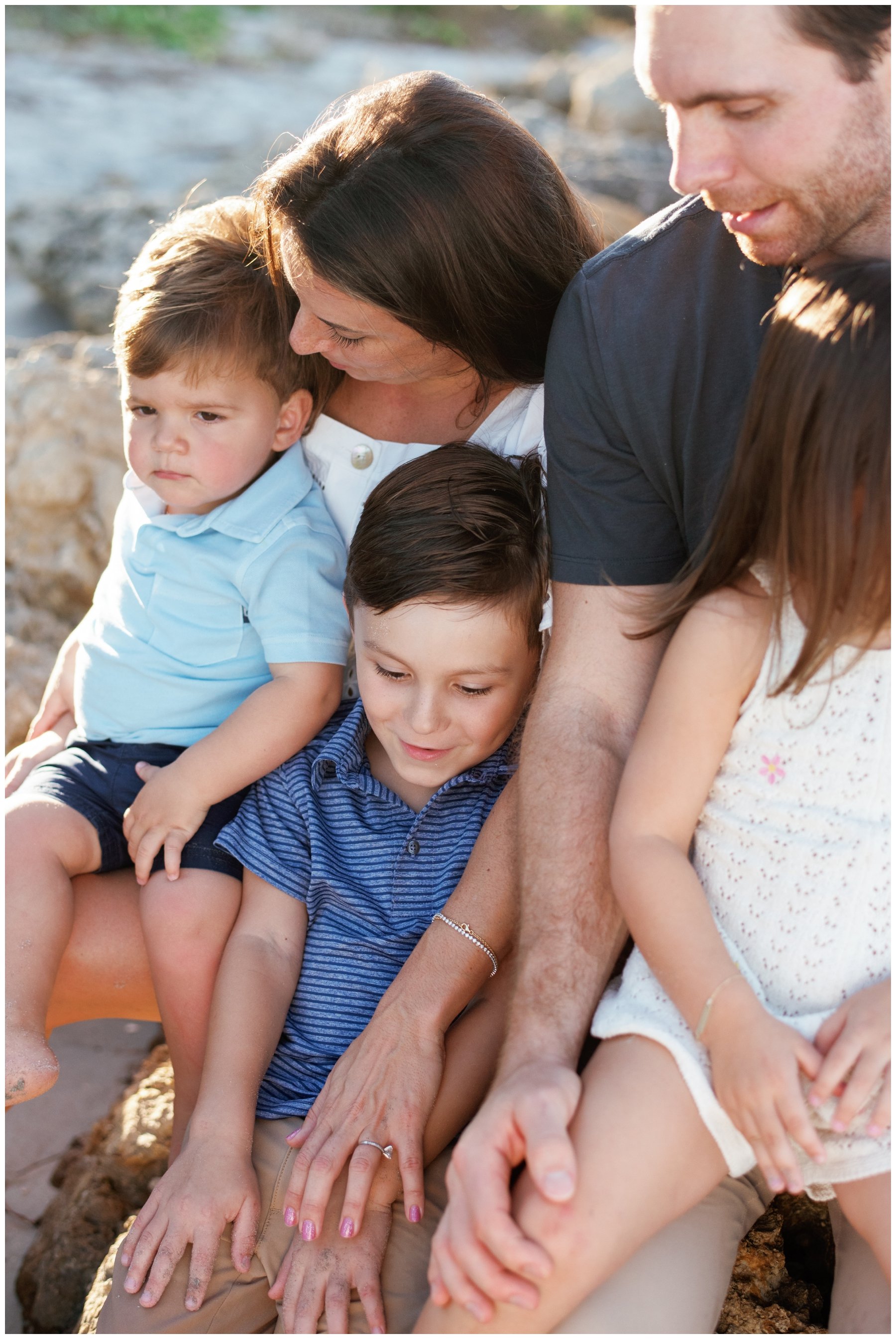 Family of five sitting on rocks on beach in Jupiter, FL | NKB Photo