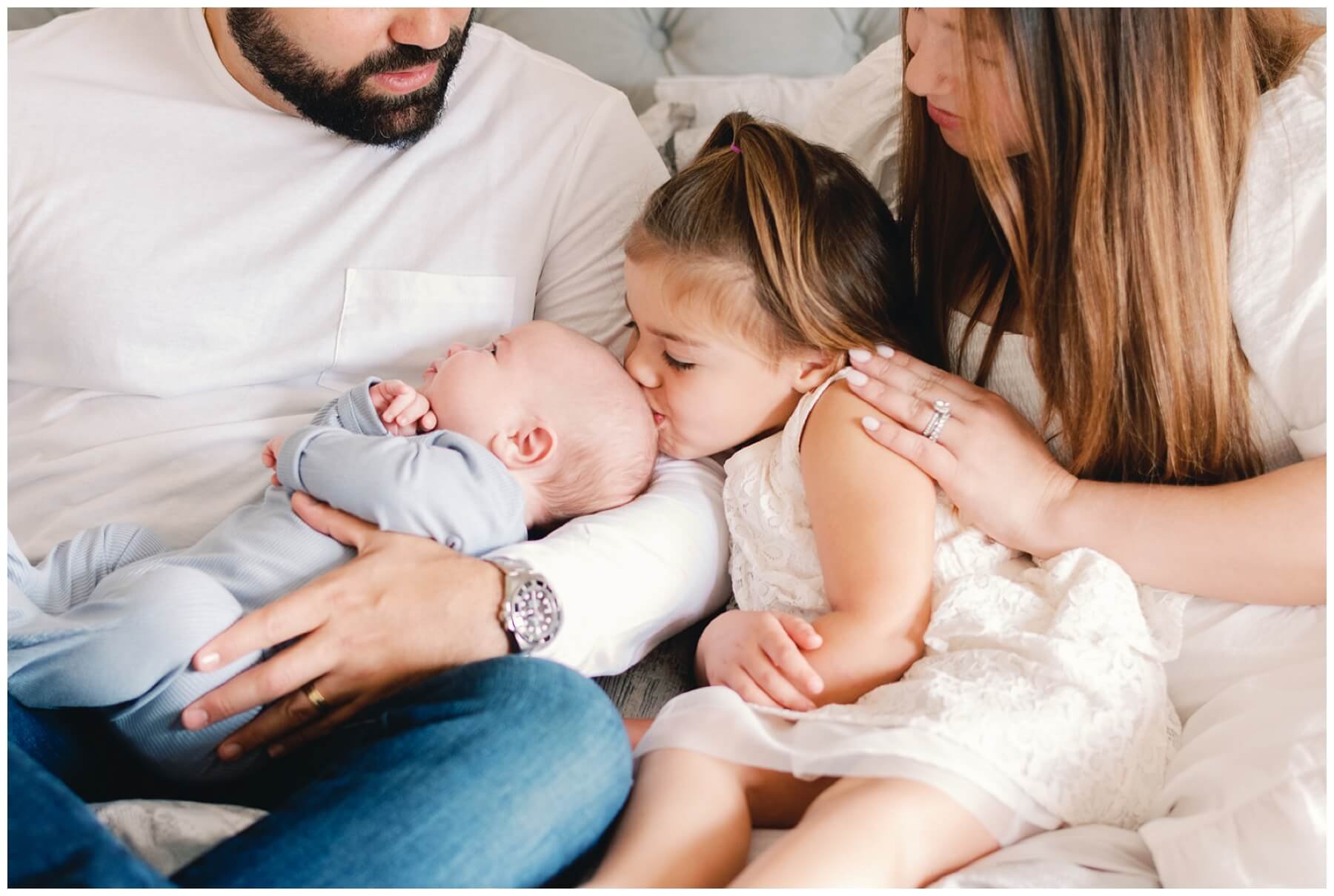 Sister kissing baby brother on head during newborn session | NKB Photo