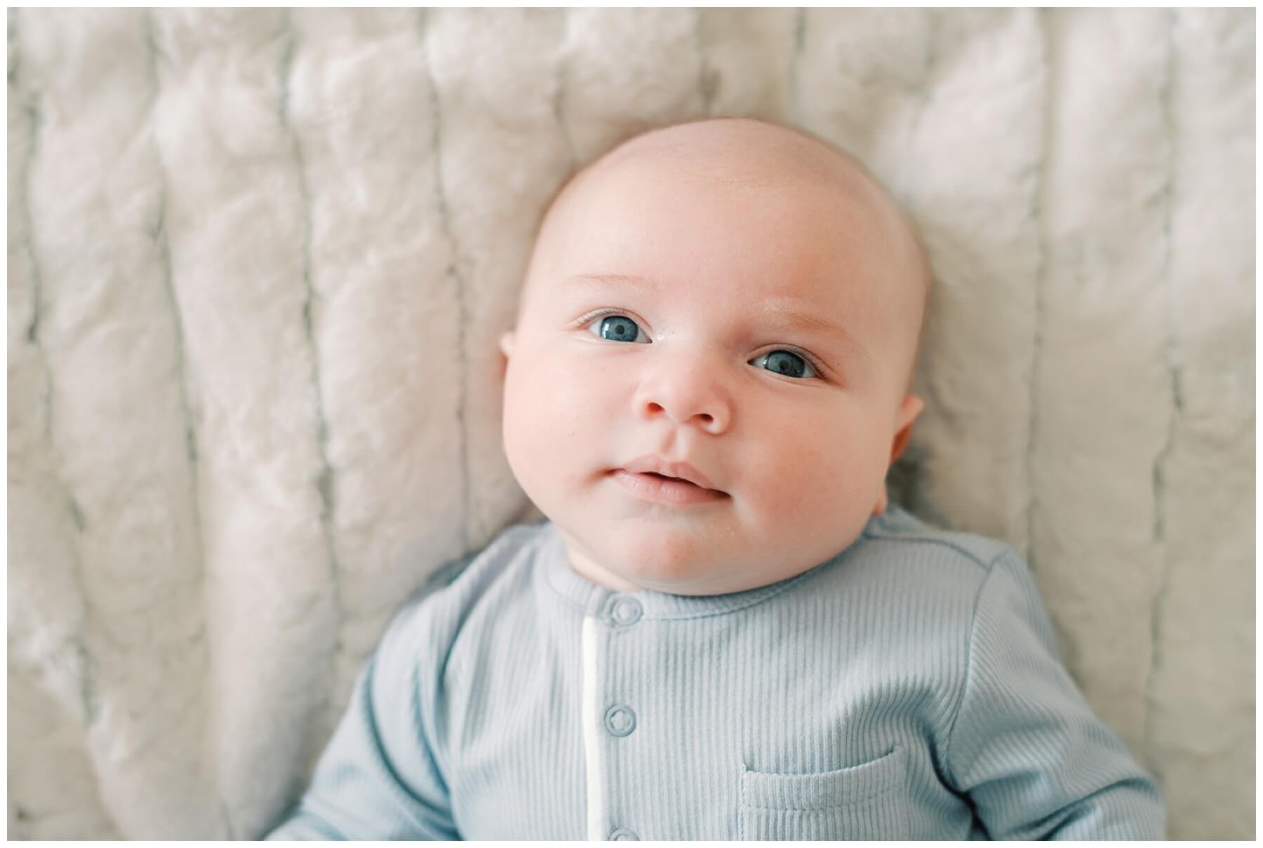 Newborn baby boy laying on bed looking up | NKB Photo