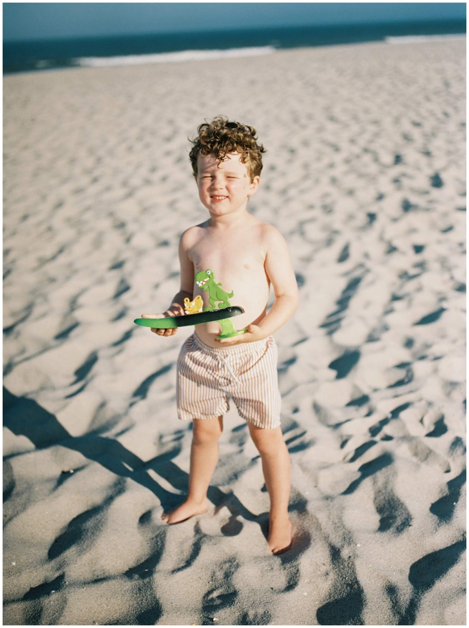 Little boy holding toy on the beach in film photo | NKB Photo