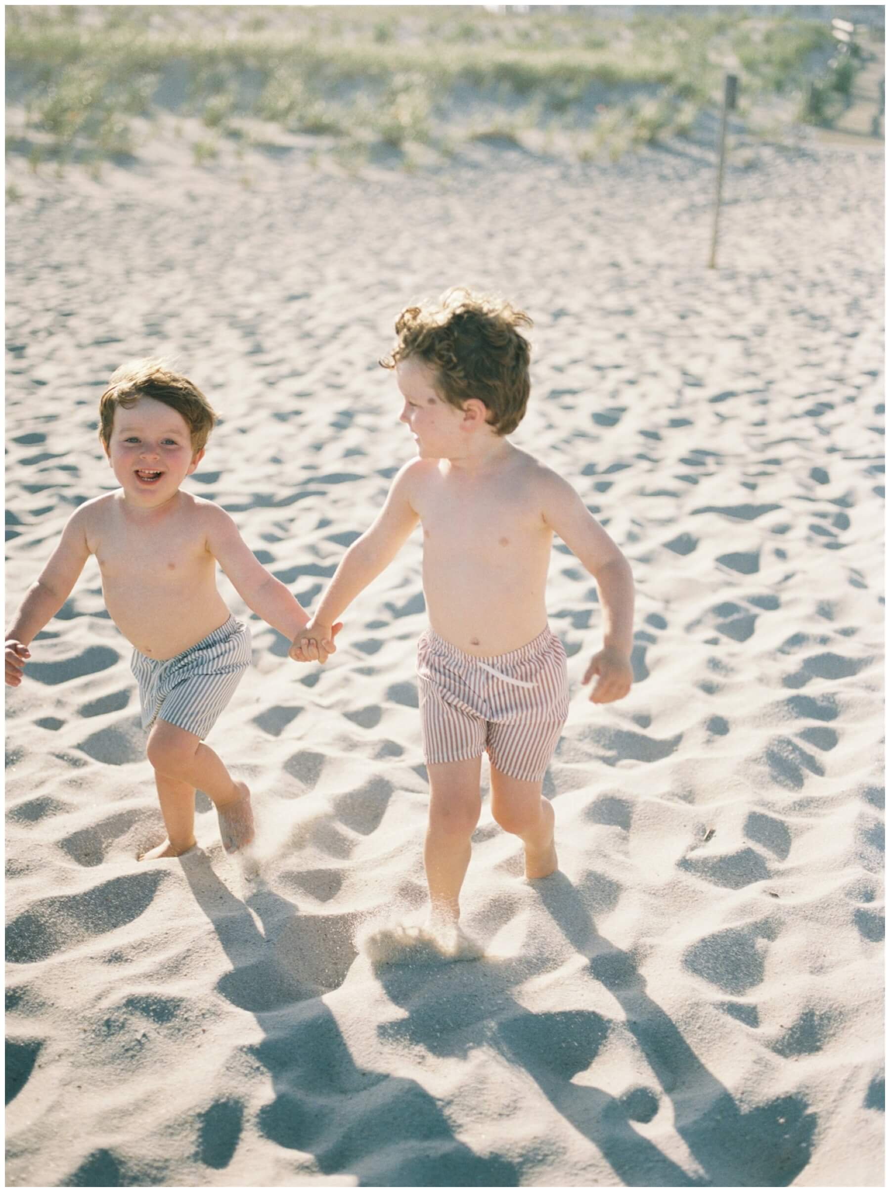 Brothers running and holding hands on the beach | NKB Photo