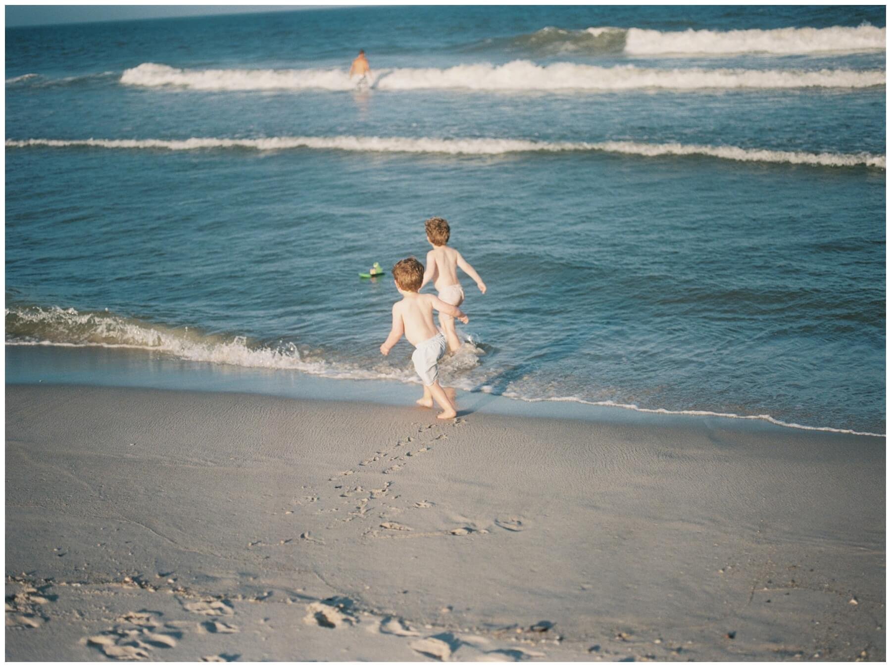 Boys chasing toy in the ocean | NKB Photo