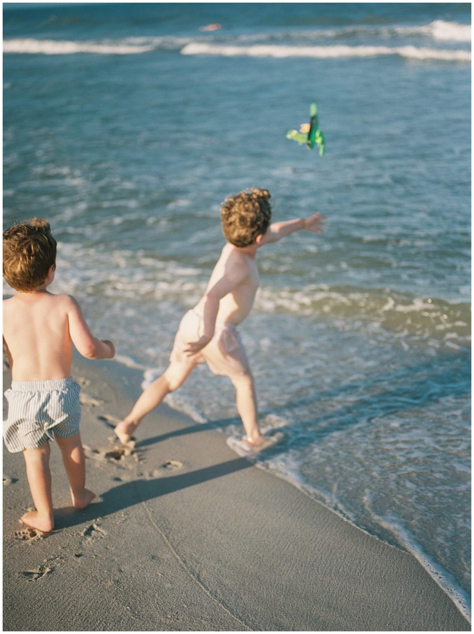 Little boy throwing toy into the ocean | NKB Photo