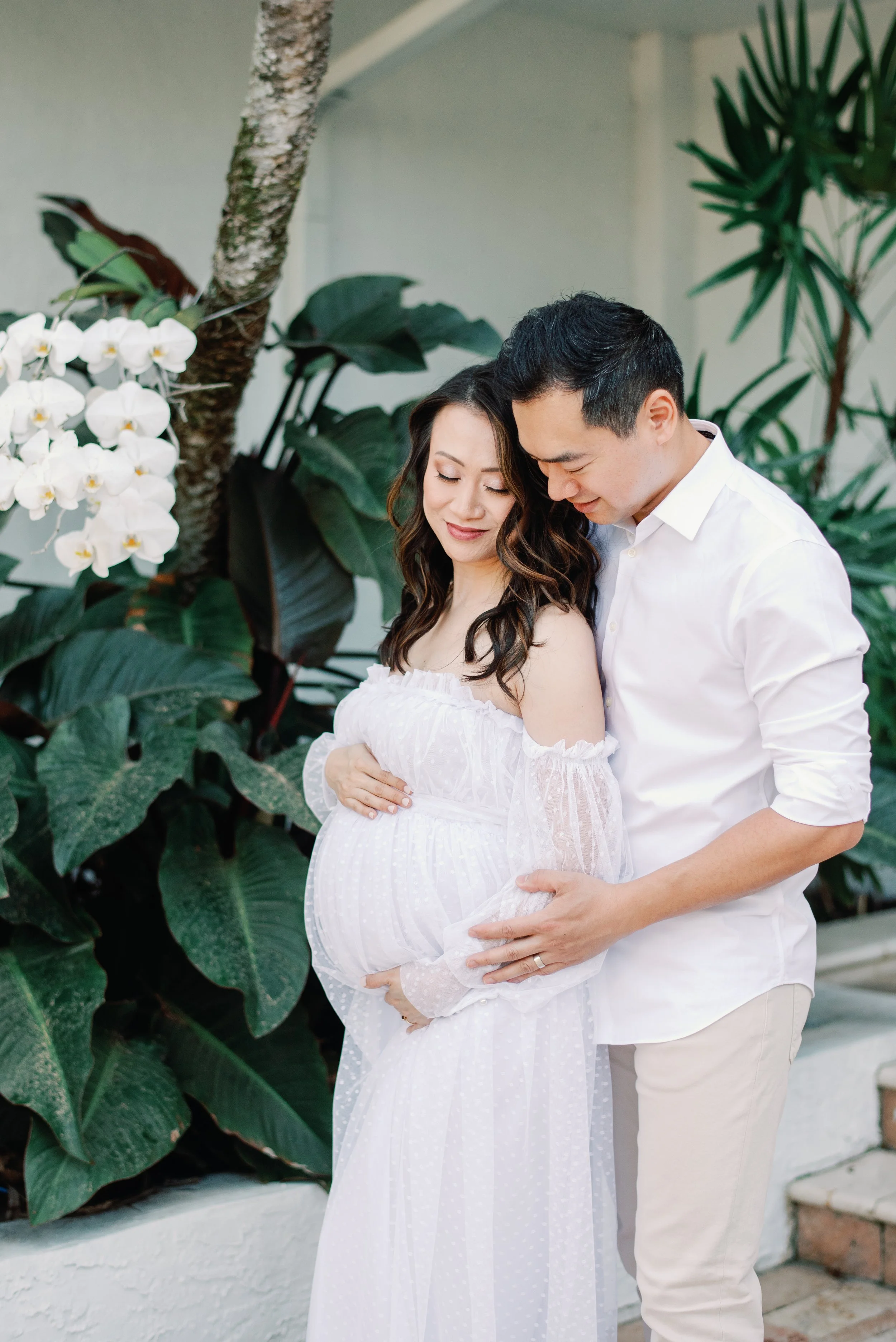 soon to be mom and dad at their home in Boca Raton posing for a maternity image in a Swiss dot dress against the lush greenery of South Florida