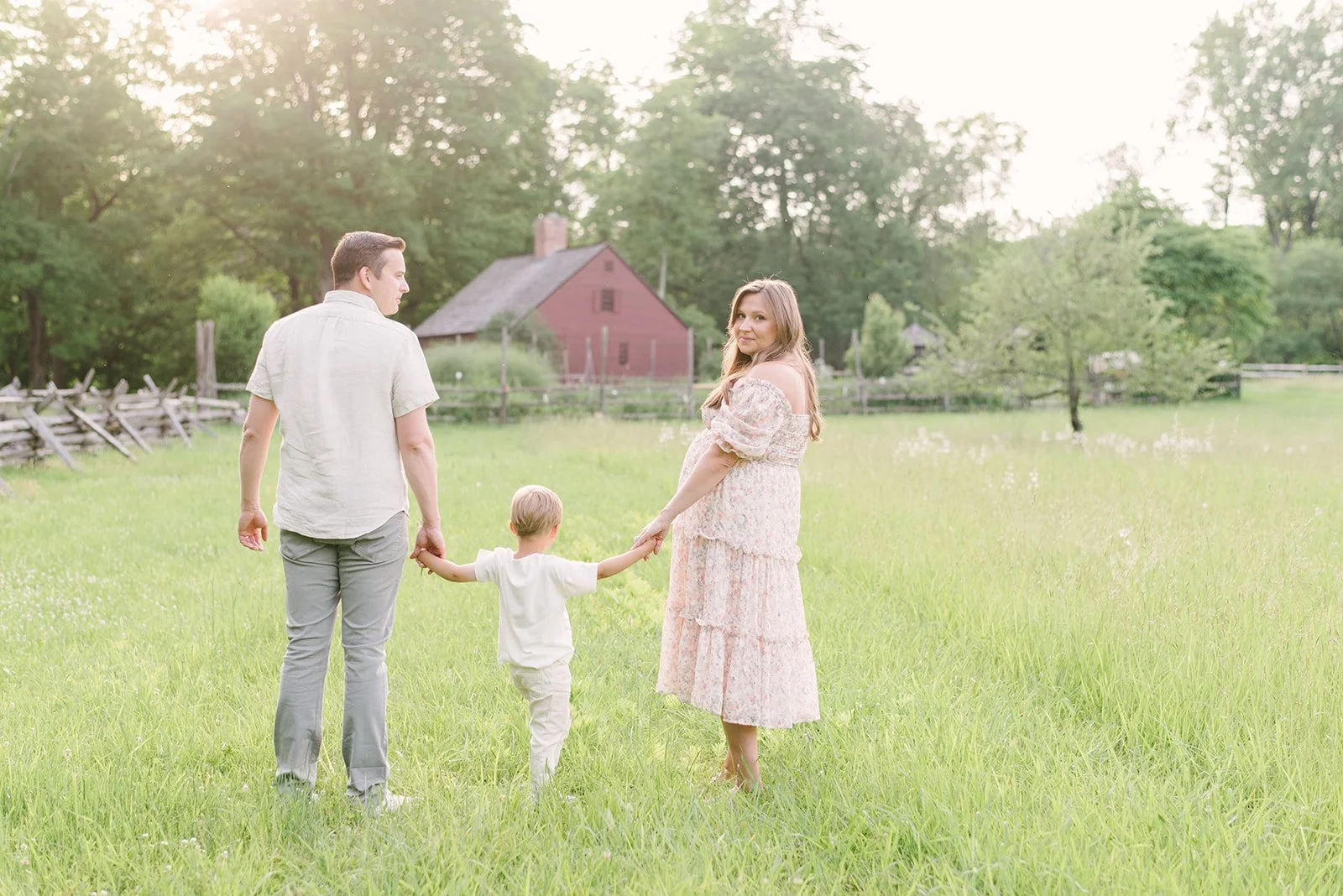 pregnant mom, dad and son in an open field in parkland with the sunsetting