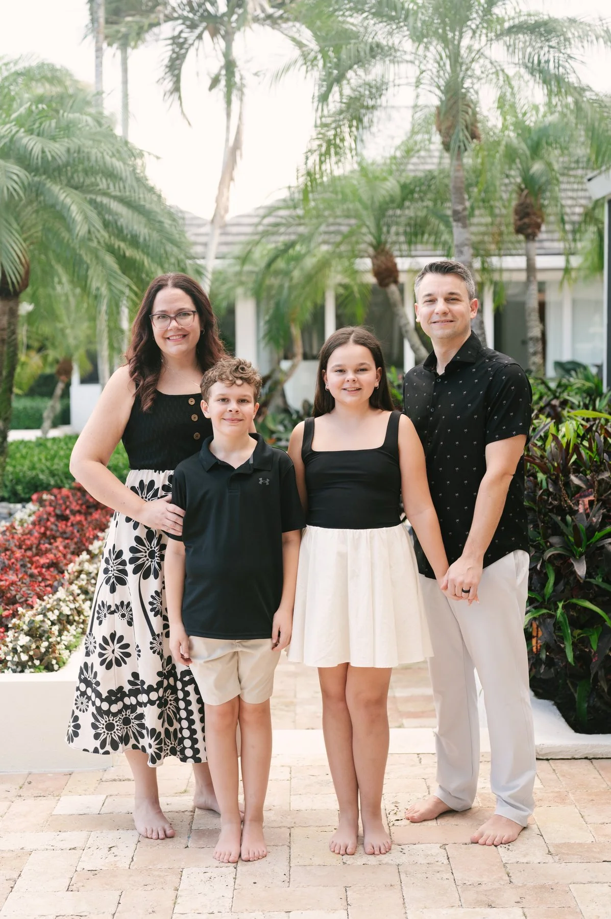 family of four in black and ivory in front of beautiful palm trees at their home in Boca Raton