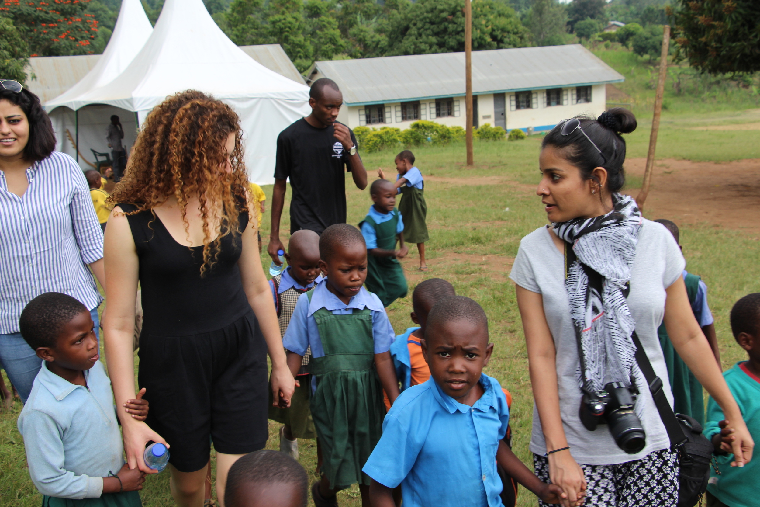 Image (from left to right) of Sukriti, Eli, Ally, and Ruchi walking hand in hand with students from Hadassa Primary School. 