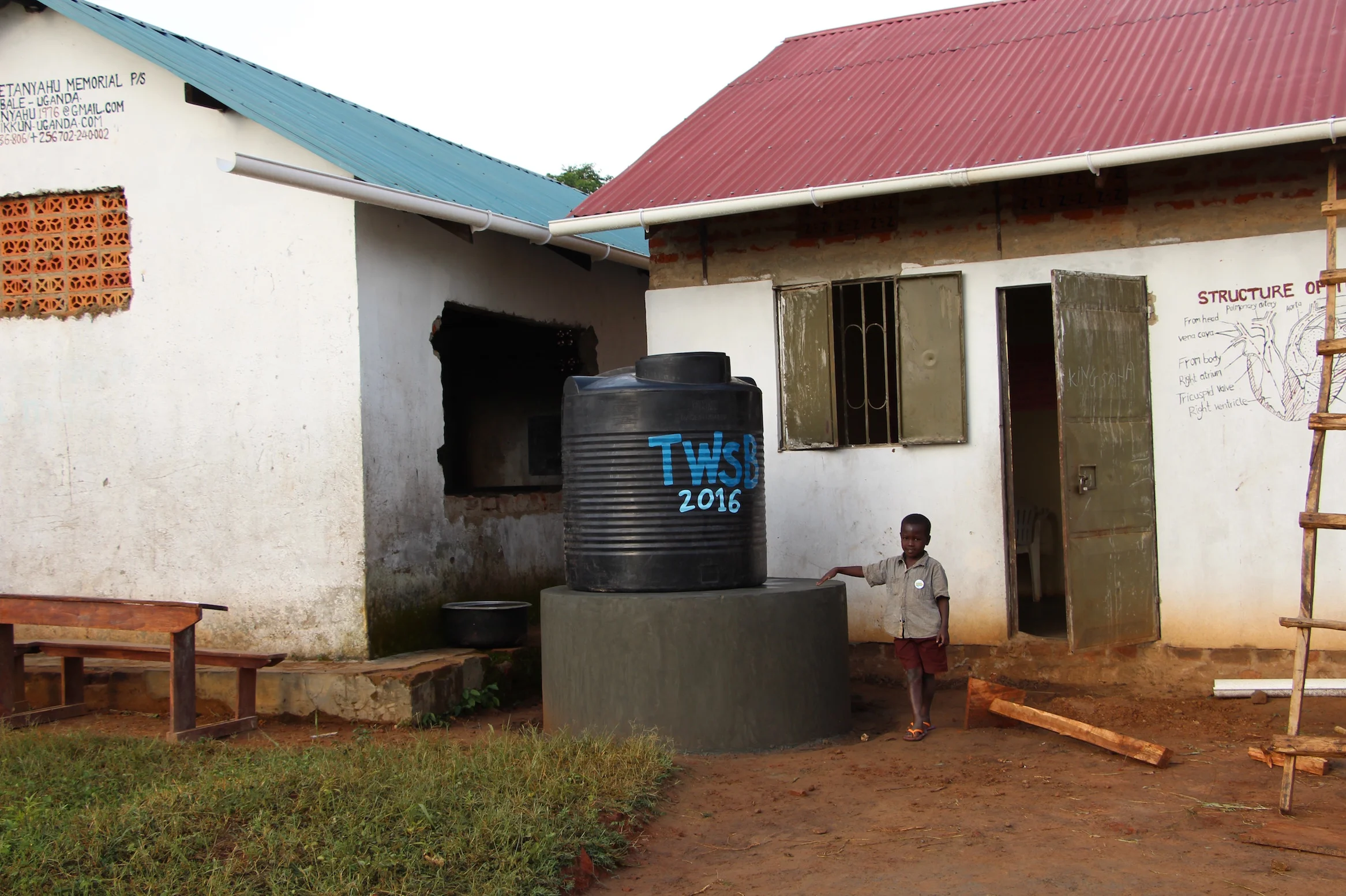 Young JJ Keki (Enosh's Son) standing in front of the new water catchment system which is the first of its kind in Putti Village. Here, rain is captured in the gutter systems and channeled down into the 1000L storage tank. From there, it is stored to water the garden and to provide drinking water when the bore hold has dried up. 