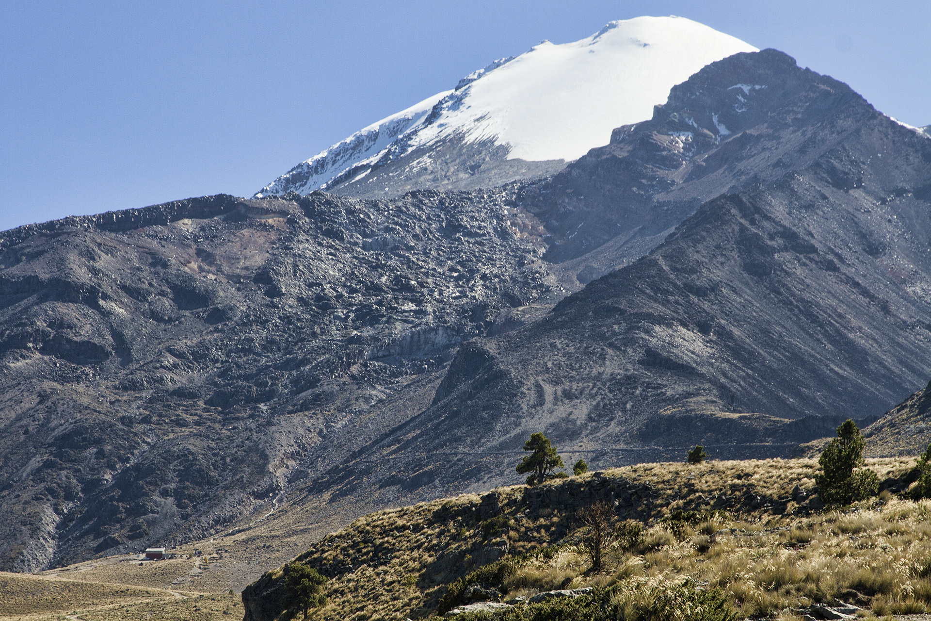  A final differential-crunching turn around a ridge and our home for the next 3 nights reveals itself. The three-story  Piedra Grande  hut sits humbly at the bottom of the scene before us, at 14,000 feet a.s.l. A faint trail can be seen running upwar