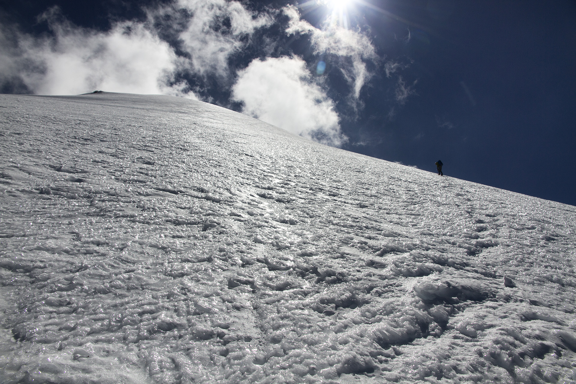  Congratulations are shared as the brief rest has been earned. Clouds begin to form, prompting us to begin our descent before the inevitable mid-day white out sets in. The descent is precarious, as patches of hidden water ice do their best to rid the