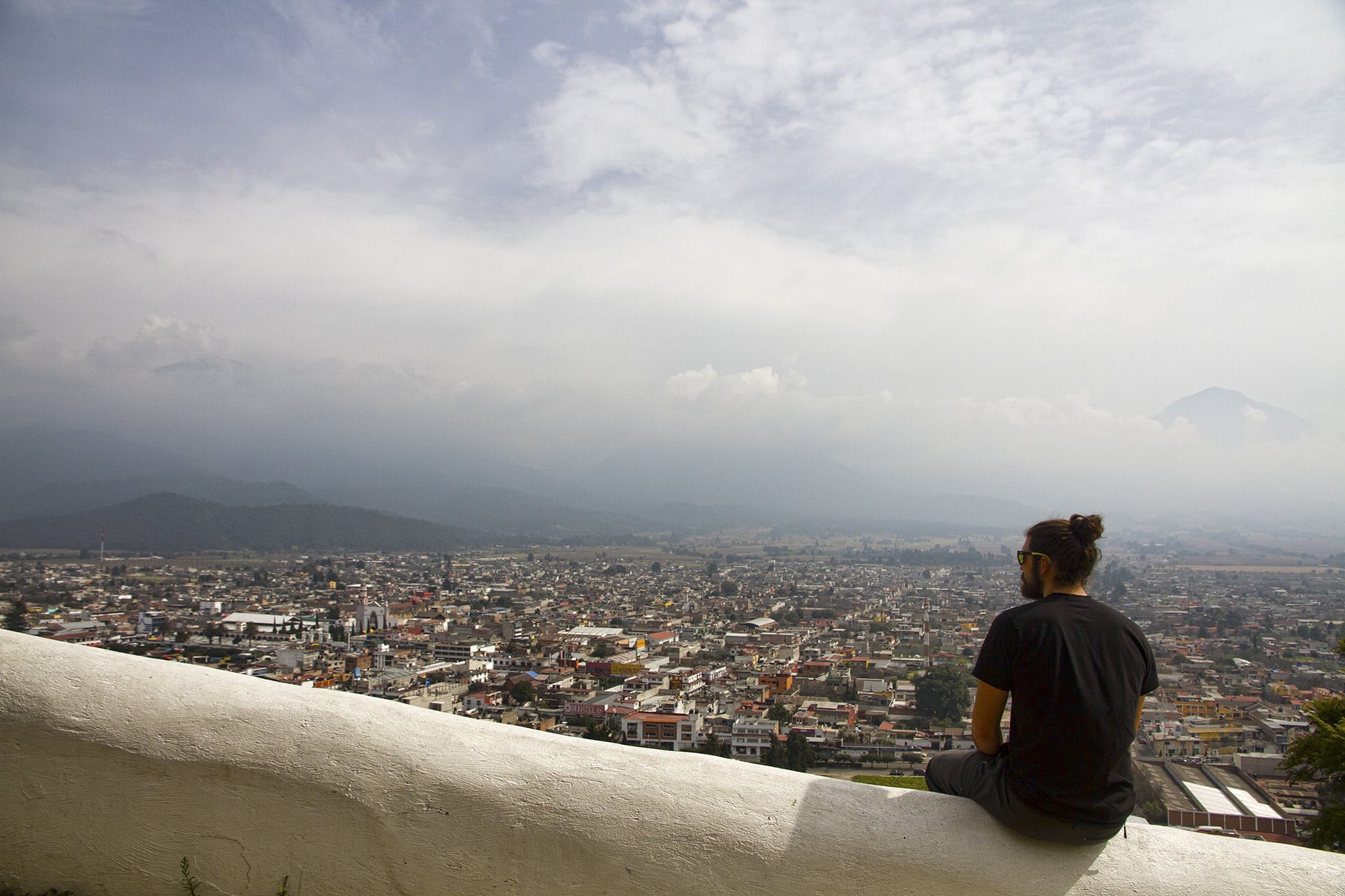  After a celebratory night of feasting on  tacos al pastor, tlacoyos  and  atole , the small hill on the outskirts of the town provides a nice view of our sleeping woman and her guardian. Down in the town square a bus waits to take us back to the cap