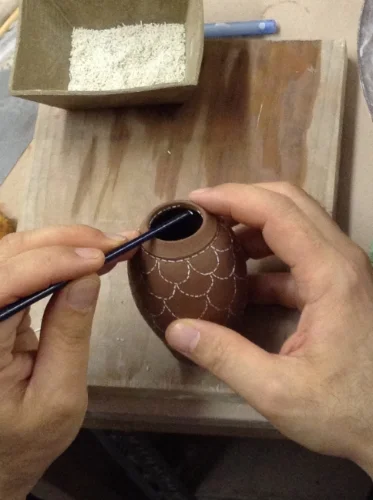 Applying stitches to wet vase with end of paintbrush