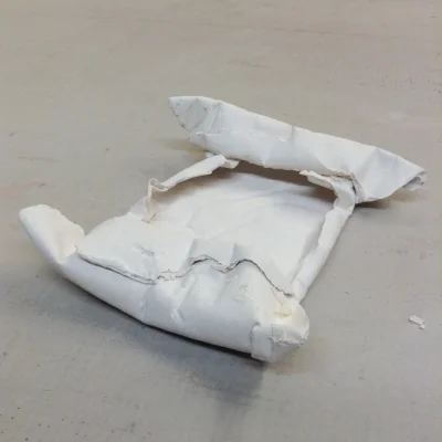 Fired form, all paper burned away, leaving many interesting folds and curves where the paper turned on itself and where the tape held the shape less flat.