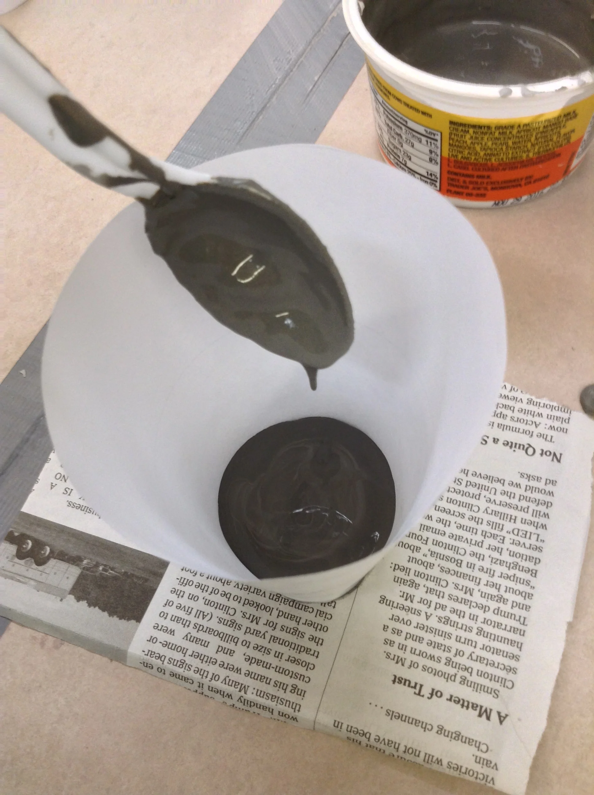 Thick clay slip added sparingly to bottom of cone, with no additional seal between cone and newspaper underneath. Slip hardens slightly on newspaper and forms fragile seal against leaking.
