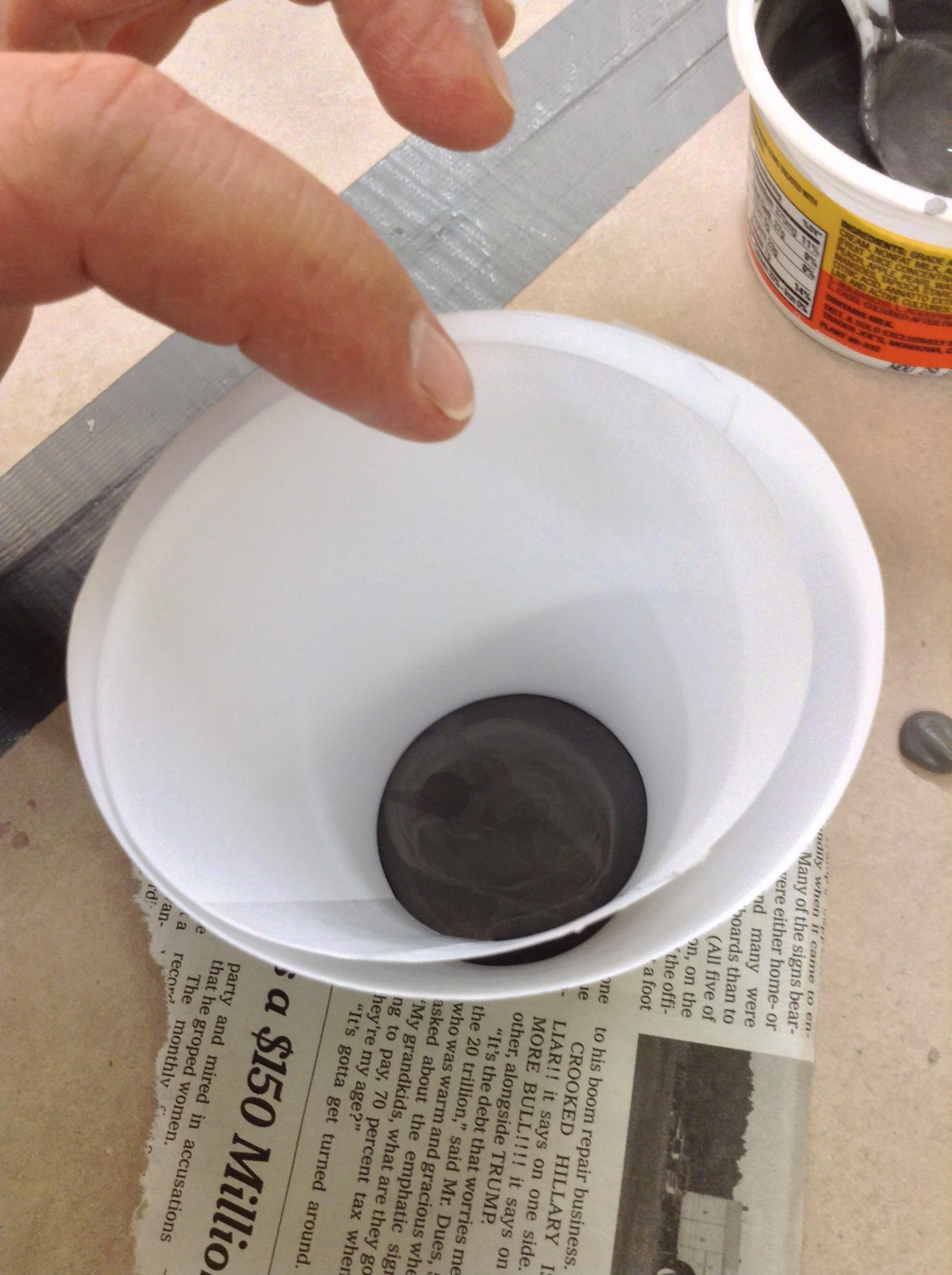 Inner paper cone, smaller, with bottom edge sunk into wet floor. Interior circle represents floor after walls are cast. Gap visible between cones creates fill space for slip.