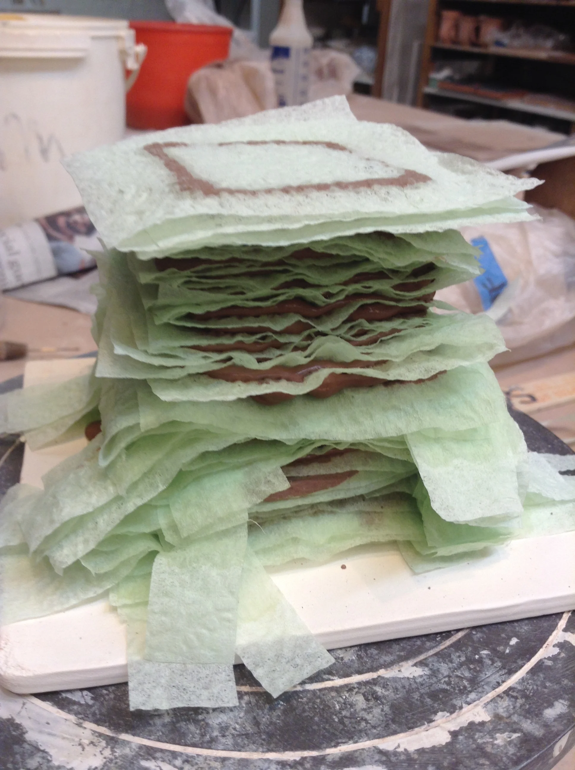 Several inches of the stacked form showing the change from napkin strips to napkin squares. The ultimate choice will be solid squares, unless there is some structure also being formed inside the form.