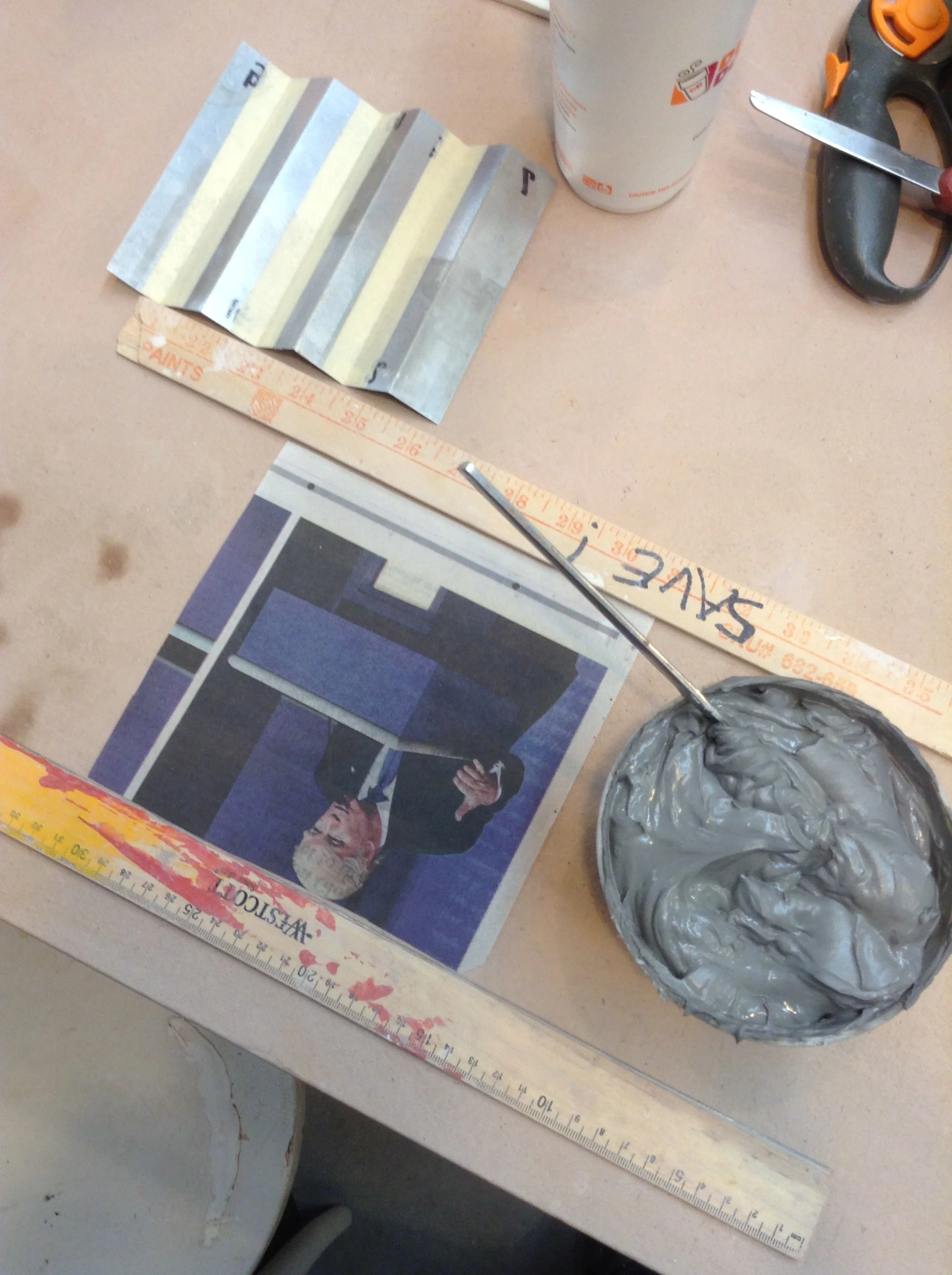Materials set up to make a paper and clay paste laminate. The newspaper square goes first and a matching one is stuck to the top. FInal goal is to have both squares of newspaper perfectly aligned with a layer of clay paste in between.