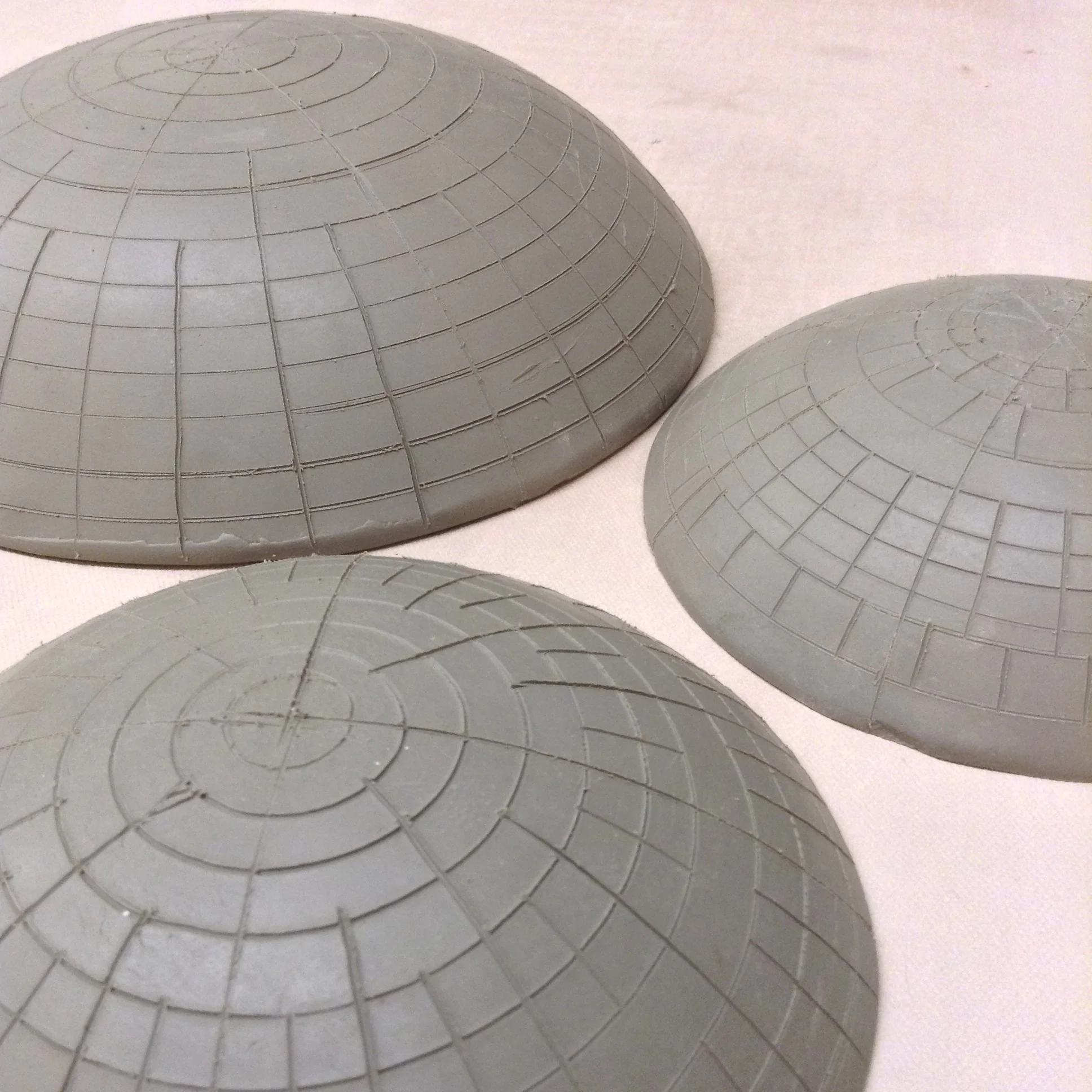 Several clay dome shapes with lines drawn on outside to indicate to me where to drill the holes. Unclear yet whether these subtle changes will matter after all is finished. But I could always make these as just normal ceramic bowls!