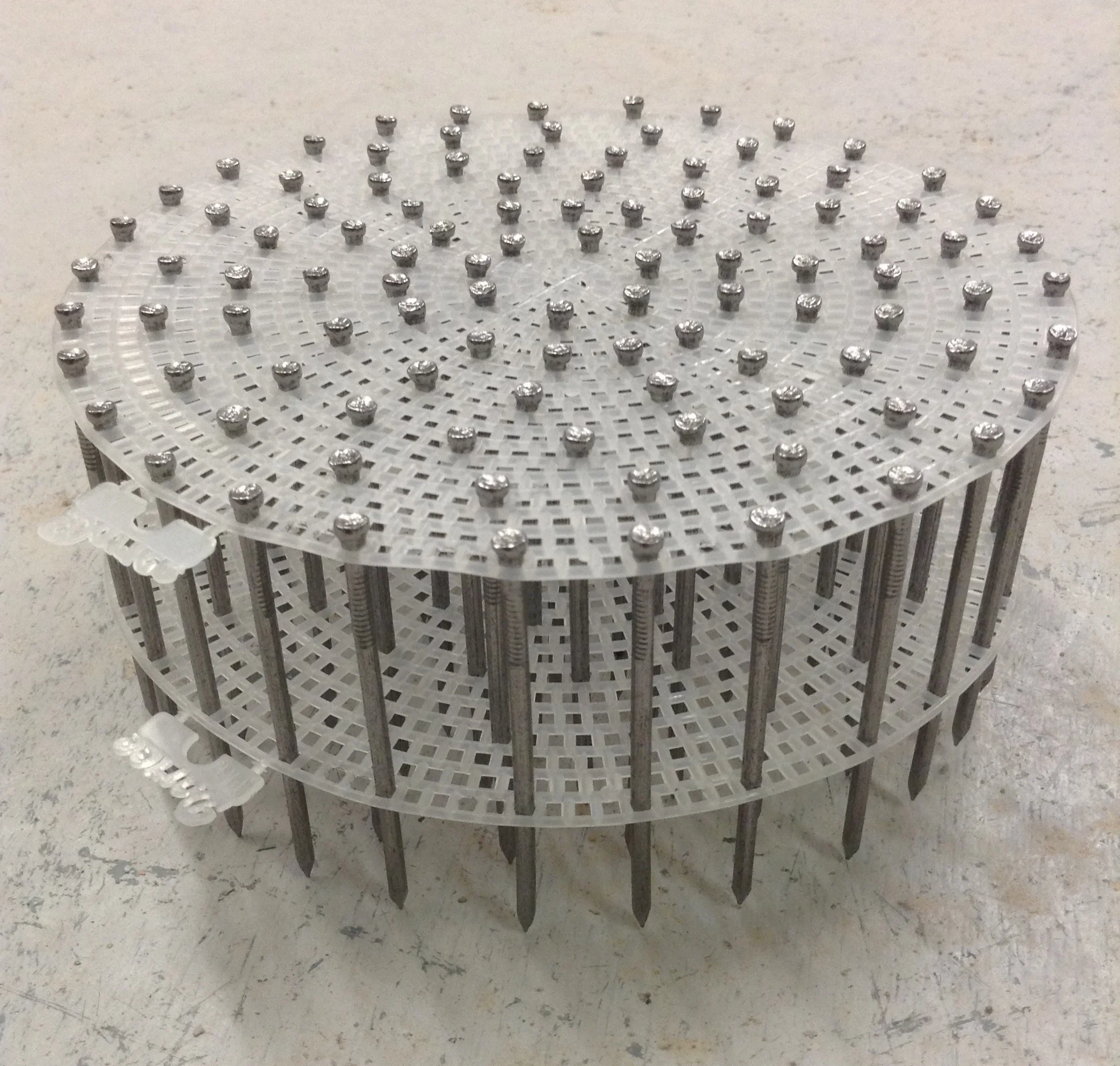 Example of using plastic embroidery mesh to align nails vertically in concentric circles. The space underneath where the points are represents the part buried in plaster. No drilling!