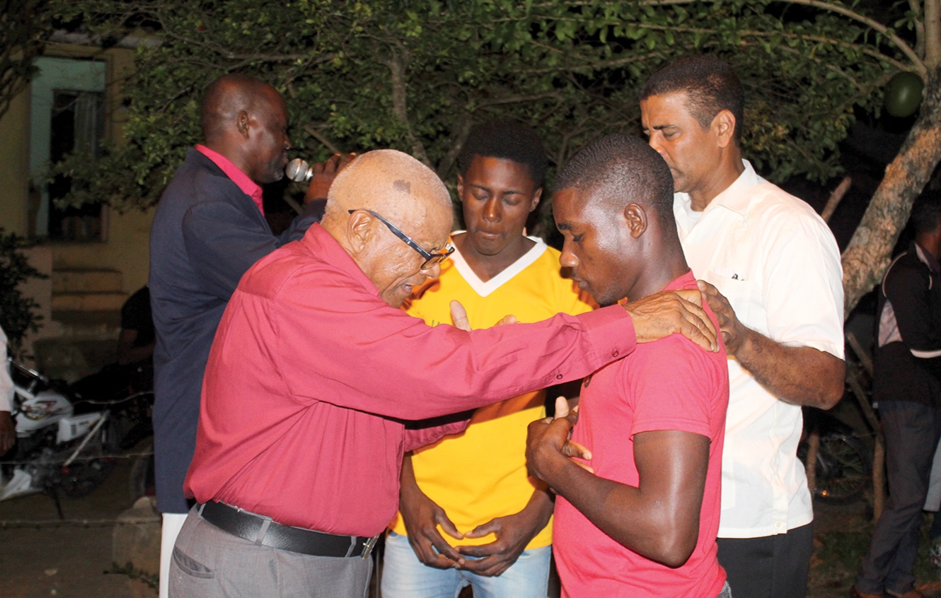 Pedro Peralta and Pastor Nicolas Santos praying with one of the men who accepted Christ during the service.