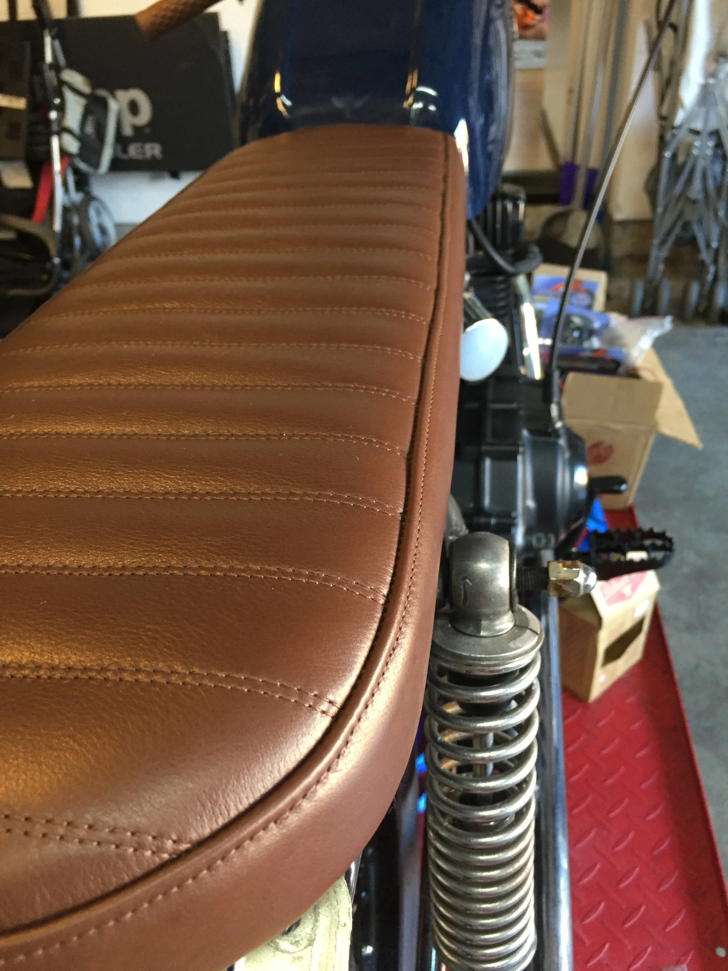 All of our seats are upholstered in house. Most of them are made with vinyl for durability. This one, however, will break in like a fine pair of gloves. It was made from a cow hide. We may even do a tank strap to match.