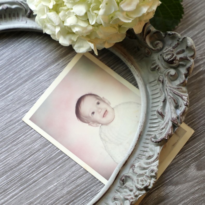 baby photo styled with an ornate frame and white flower