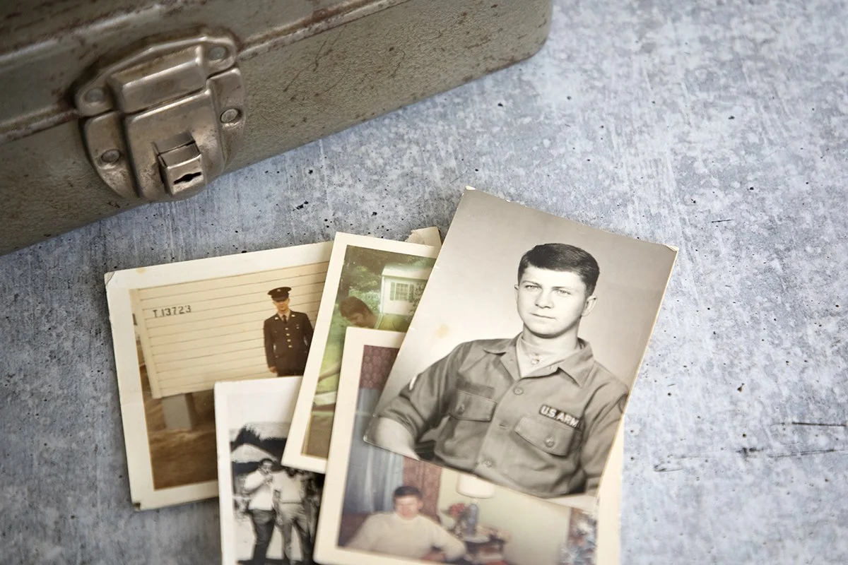 weathereed tin box alongside an array of old photographs of a U.S. Army veteran in uniform