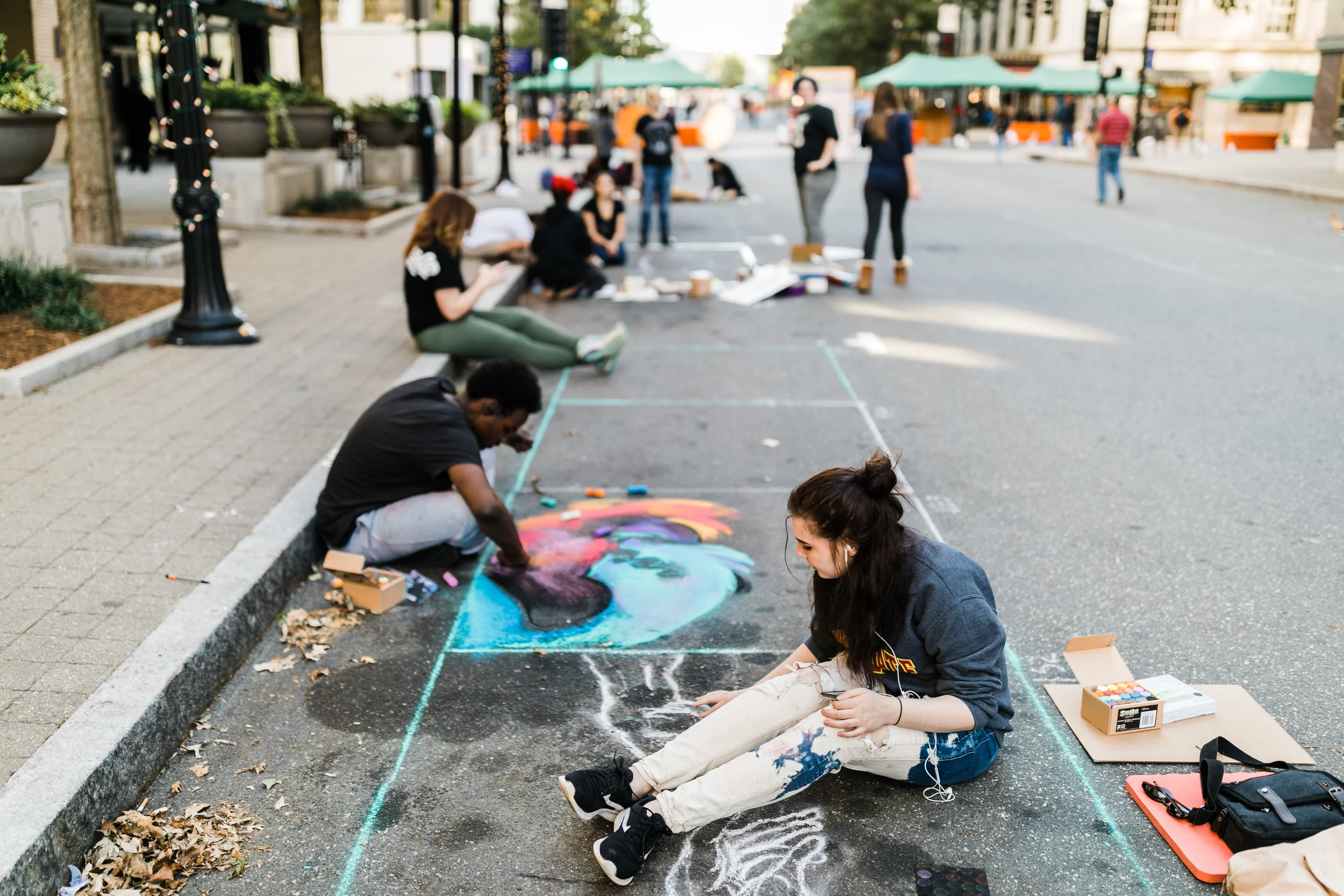 Two young adults painting with chalk on Fayetteville St.