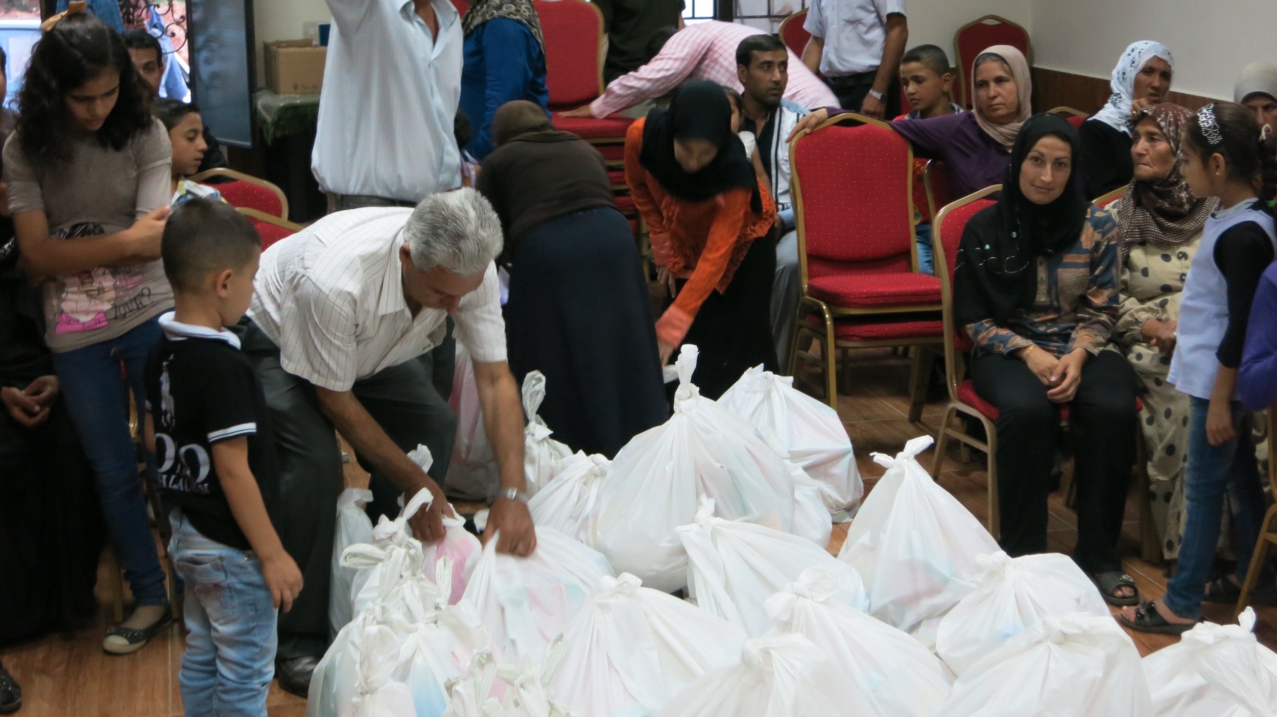 Refugees receive food and aid parcels from at the Call of Hope Center in Lebanon 