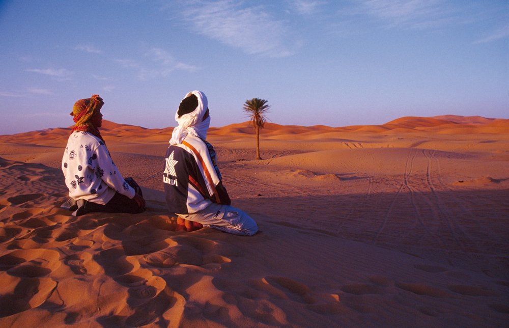 Bedouin Muslim's in North Africa kneel in the desert.