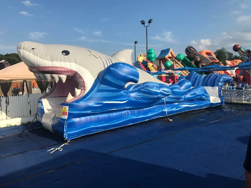 Watch in anticipation as your party guests slide their way right through the wide gaping jaws of a great white shark! The Shark Slip and Slide is an exhilarating ride. Experience the rush of being carried by the water as you glide down the inflatable slide to the splash platform. Then, turn around and go for it again, as you will surely want to after such a thrilling ride! Bring the water park straight to your backyard. What a great jaw-dropping surprise this would make for a marine life lover, or any friend with a wild side! It is quite a sight to see this giant toothy shark occupying your lawn. If you need an attention grabbing, water sporting, refreshing source of entertainment, we have you covered with this sensational slip and slide. People Per Hour: 60+ Power Requirement: (1) HP Blower Set-up Time: 1 Hour Space Required: 30’ x 14’ x 12’
