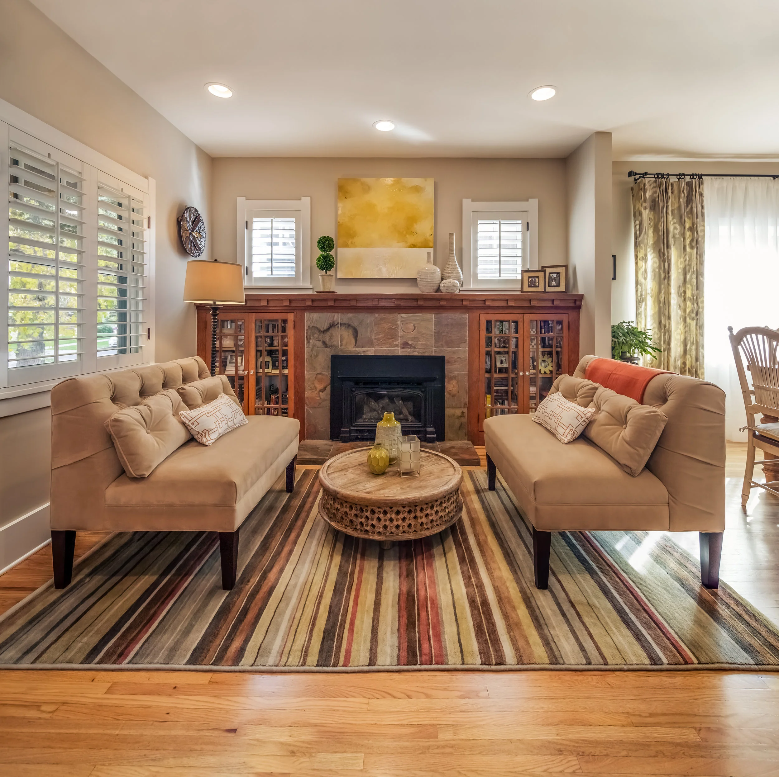 In the bungalow's very small, original living room we placed two matching settees to unify the small space and maximize seating without it looking too cluttered. &nbsp;I added a custom, mahogany mantel to the original bookshelves at the fireplace. &…