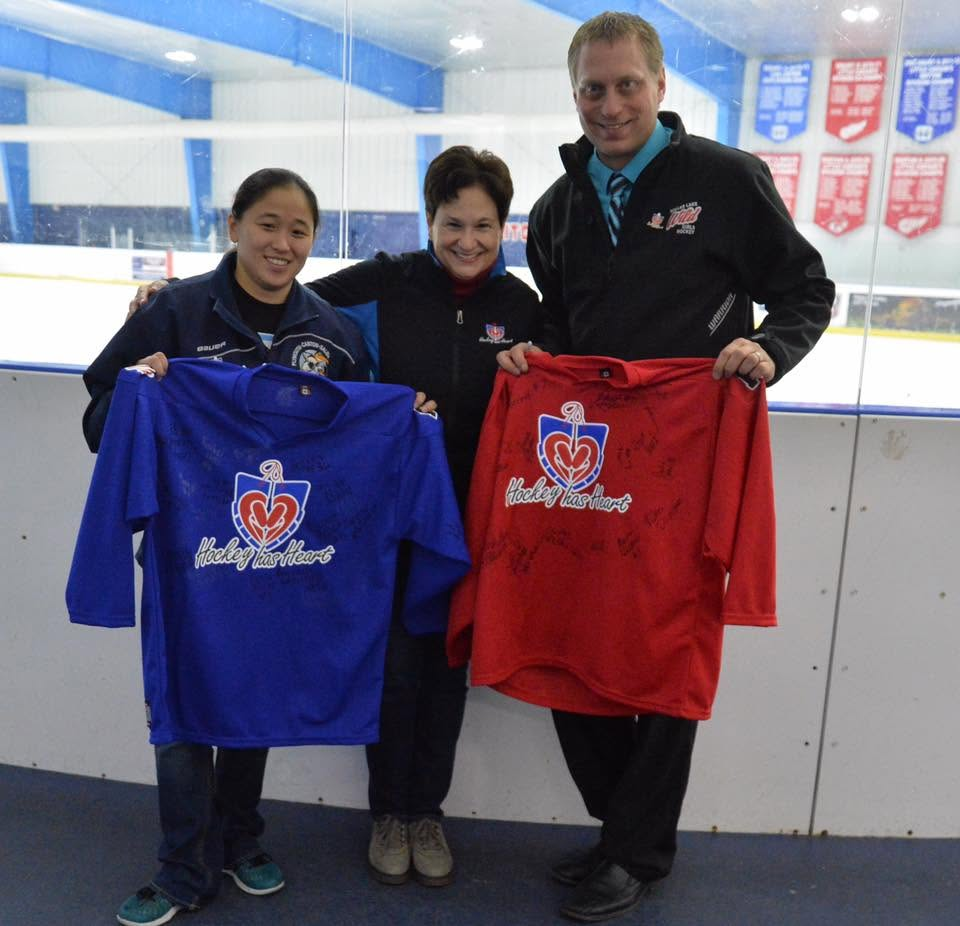Hockey has Heart volunteers holding signed hockey jerseys