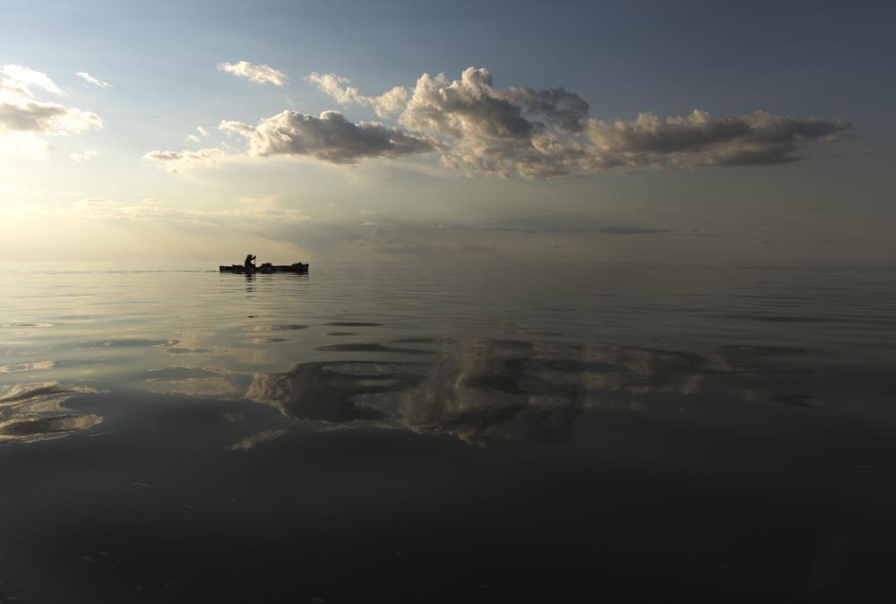  Meeting a few big fans on the water and adding under calm skies and reflective water, Mike Rata paddles all day and becomes wind bound by night fall on Lake Winnipeg, Manitoba. 20170804.  Photo/David Jackson 