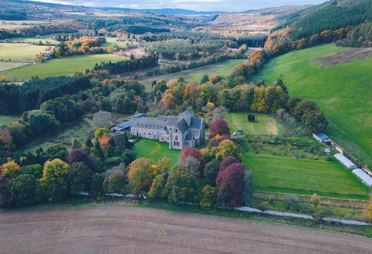 Aerial view of Pluscarden Abbey among trees and fields in Moray