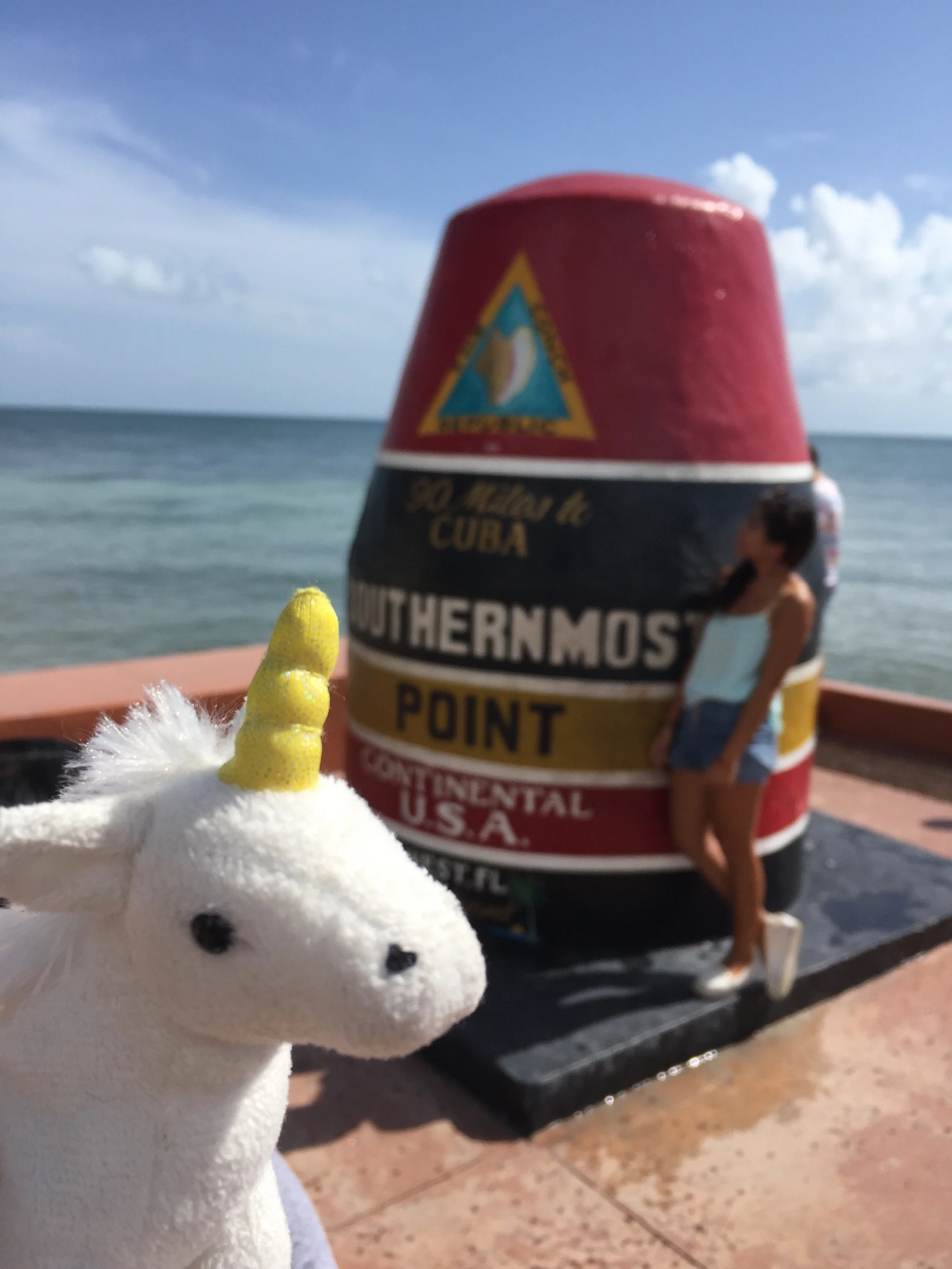 Opal the Unicorn visits the Southernmost point of the United States, where the line to get a solo photo was so long, she decided it was best to forego the queue all together and include a stranger in her selfie.