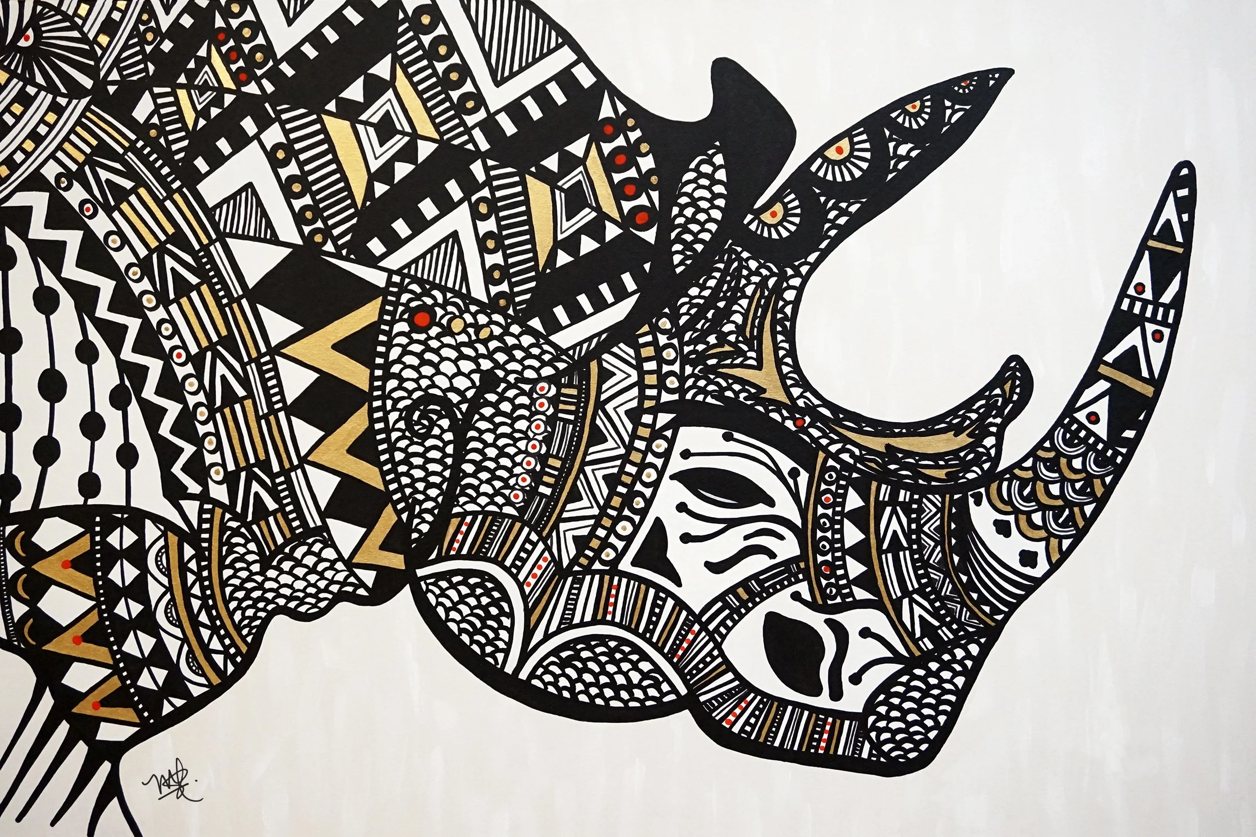 A black and white graphic illustration of an elephant created with intricate tribal patterns and designs, accented with small red and gold spots.
