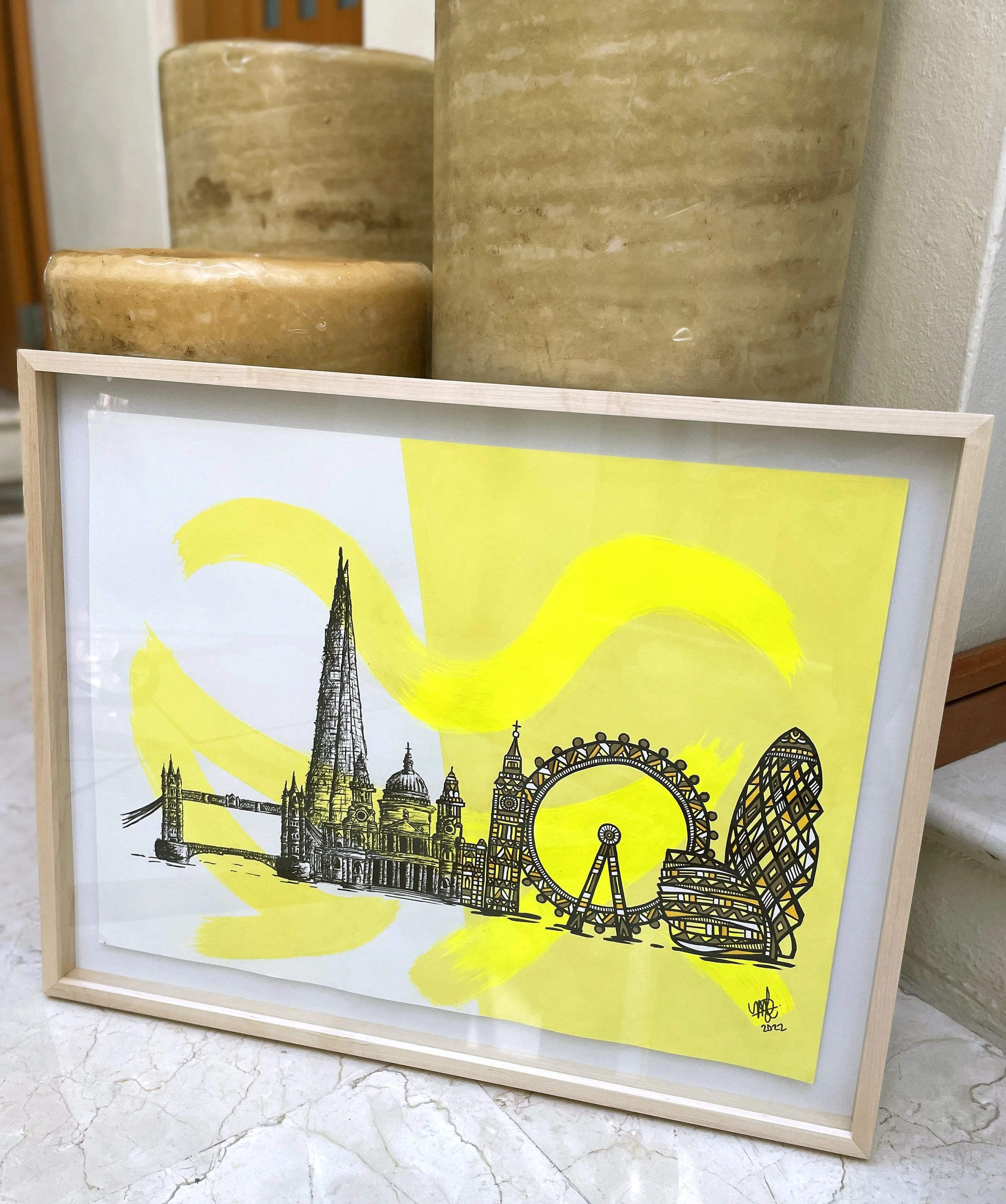 A framed illustration of London landmarks including Tower Bridge, The Shard, Big Ben, the London Eye, and The Gherkin, with yellow abstract brushstrokes in the background.