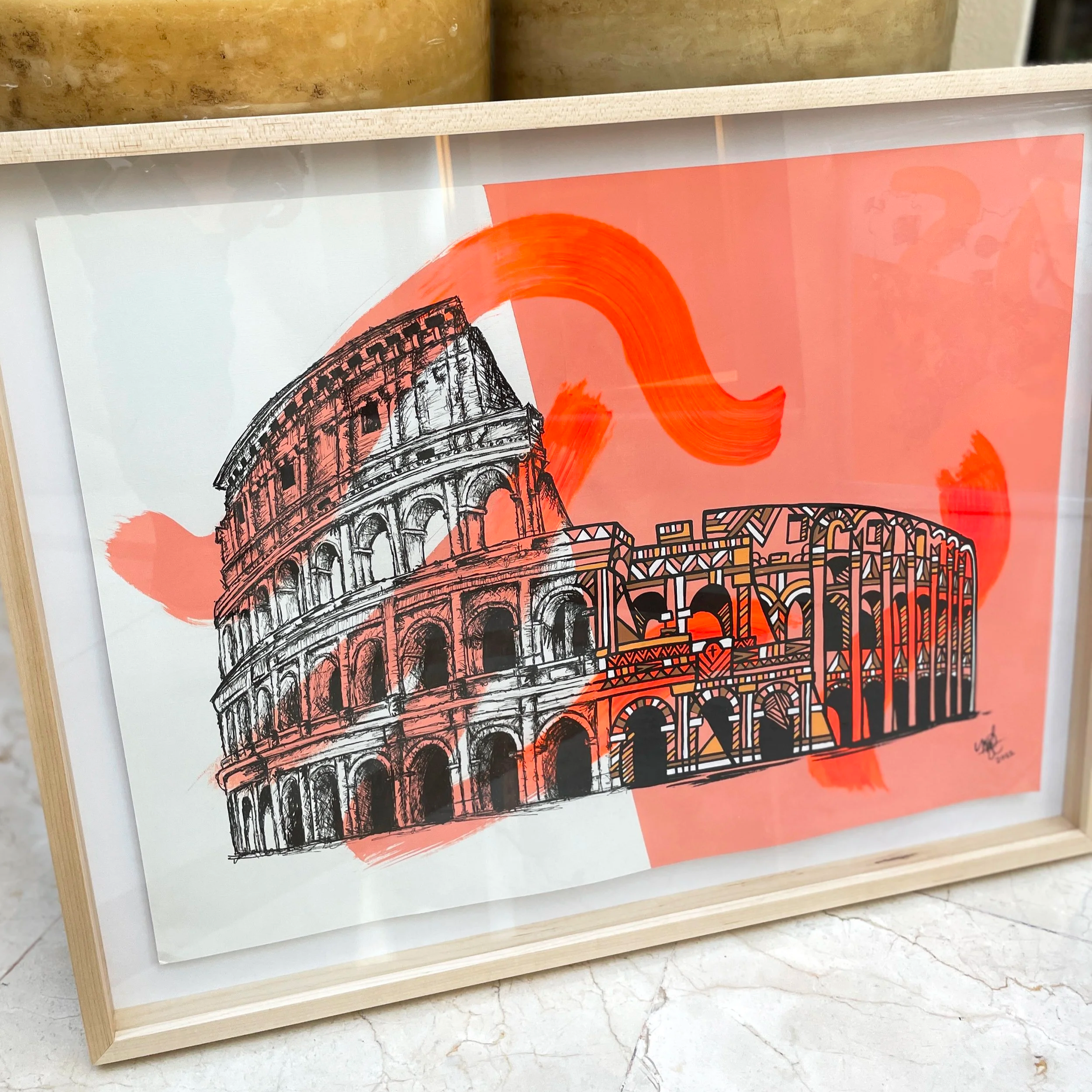 Artwork featuring a black and white line drawing of the Roman Colosseum, overlaid with a red abstract brushstroke, enclosed in a light wood frame.