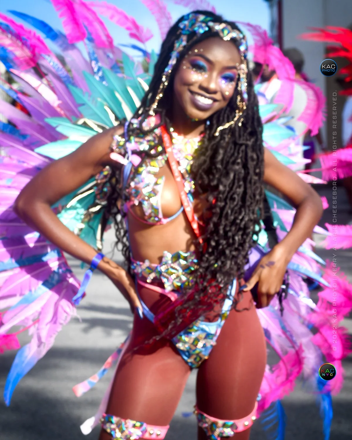 kac_photo-220802-warrens-kadooment-smiling-lady-pink-teal-purple-feathers-1-1500-vert.jpg