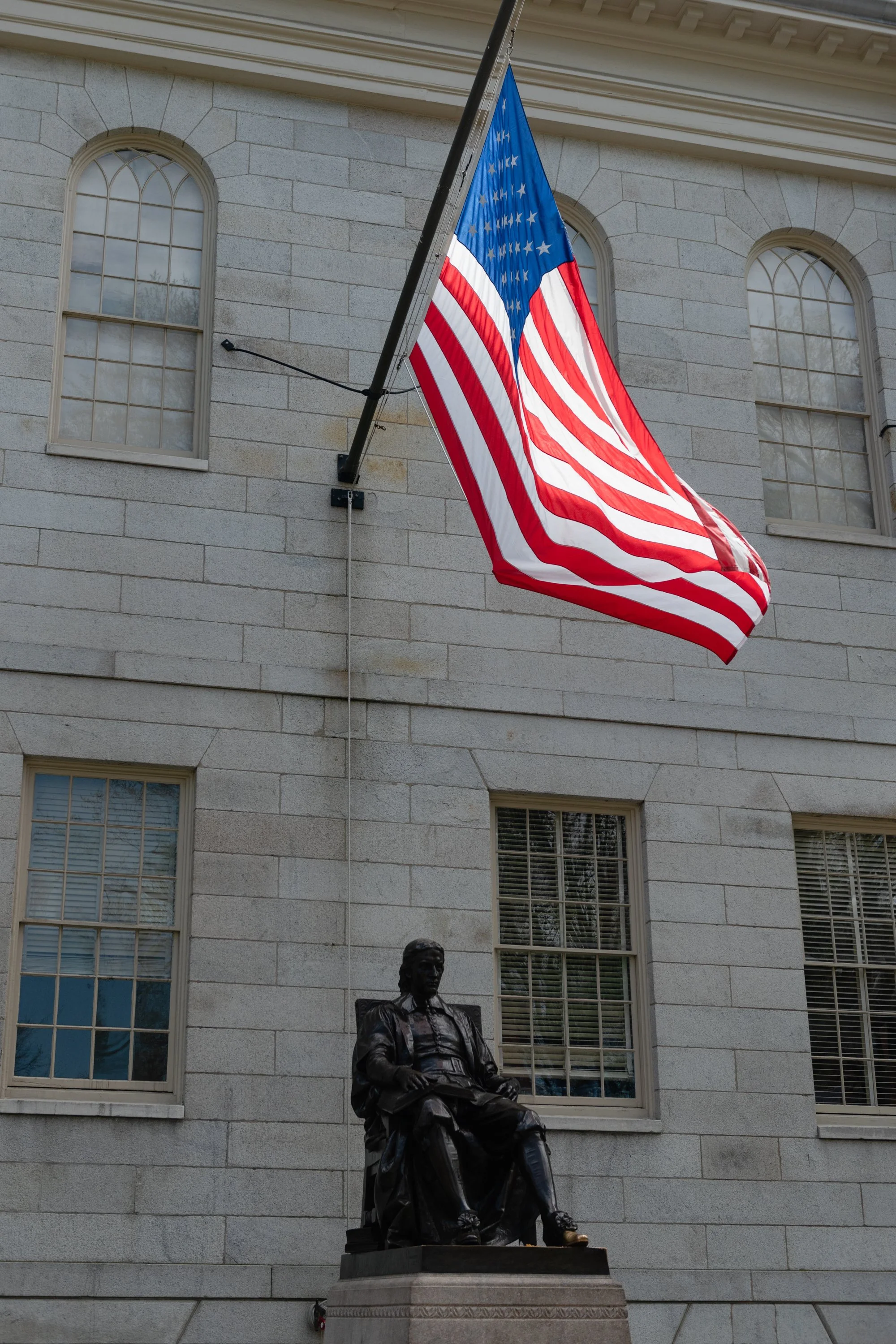 The American flag hanging above the John Harvard statue on Harvard campus.